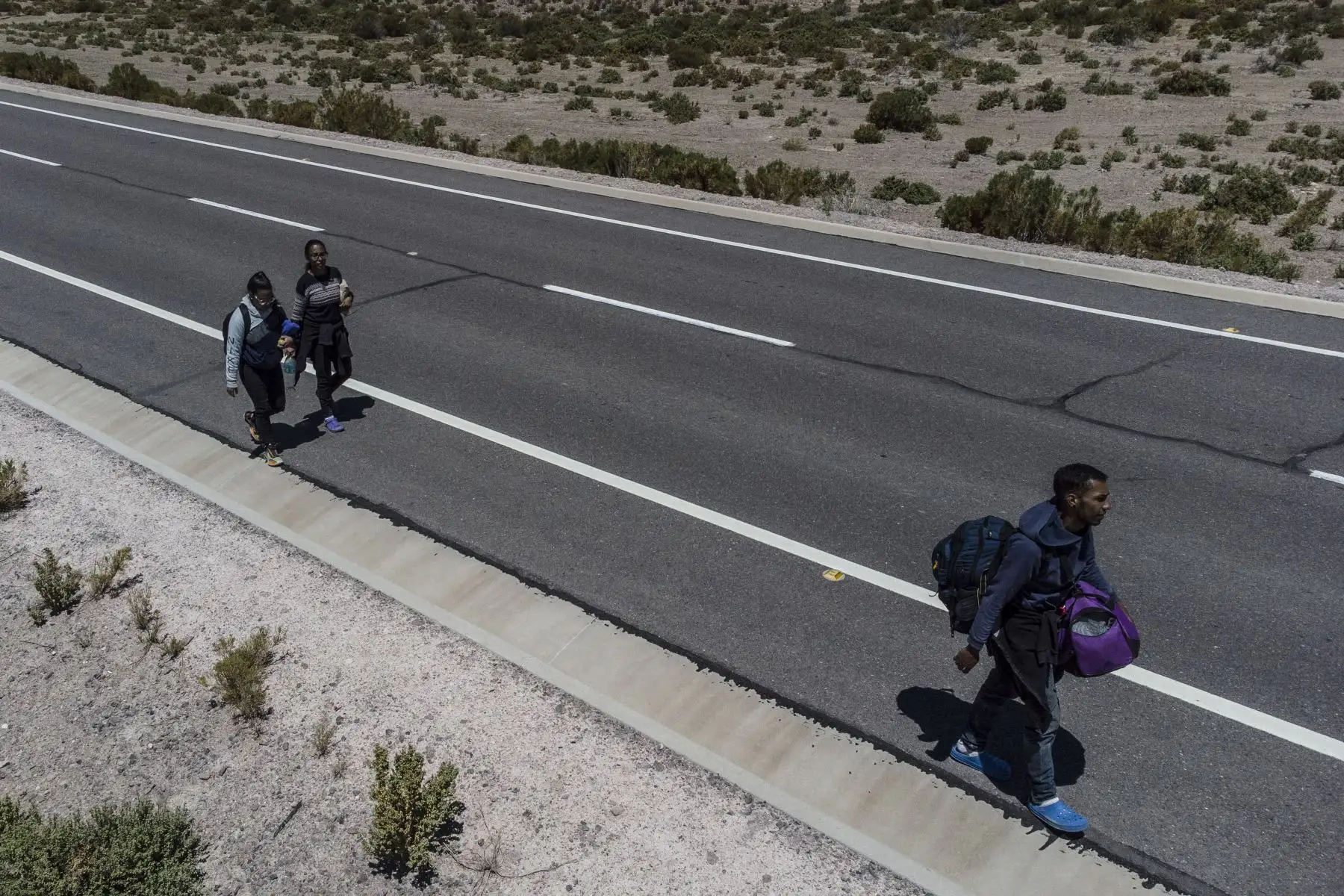 Los migrantes venezolanos Reinaldo, 26, Anyier, 40, y su hija Danyierly, 14, caminan por la carretera camino a Iquique, luego de cruzar desde Bolivia. Foto: AFP