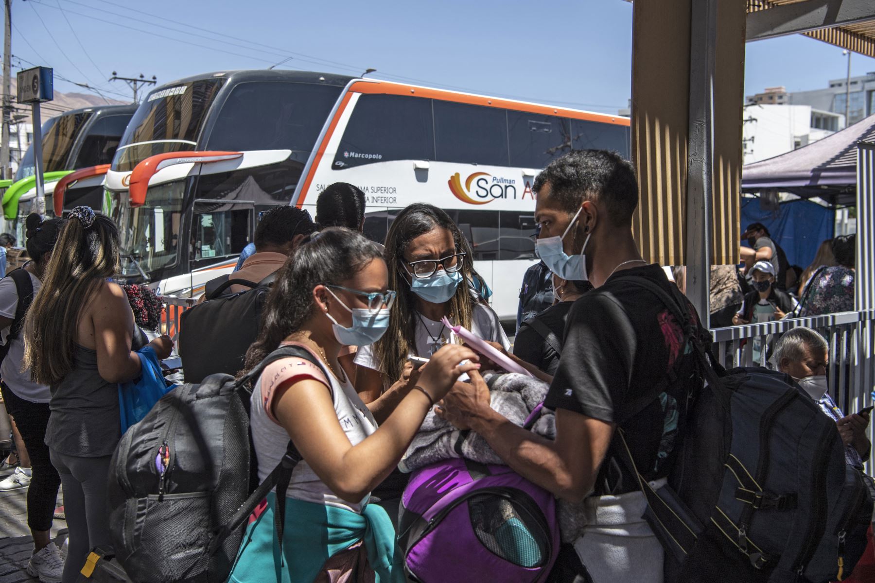 Los migrantes venezolanos Reinaldo, 26, Anyier, 40, y su hija Danyierly, 14, se preparan para abordar un autobús hacia Santiago, en Iquique, Chile. Foto: AFP