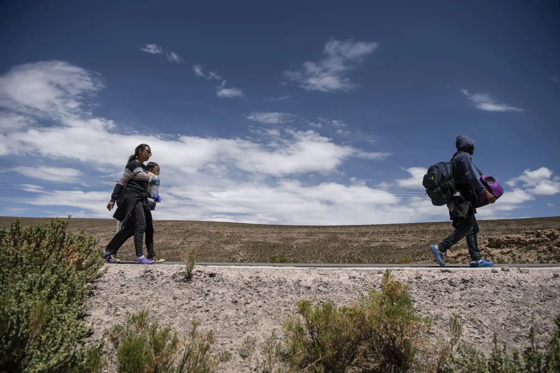 Los migrantes venezolanos Reinaldo, 26, Anyier, 40, y su hija Danyierly, 14, caminan por la carretera camino a Iquique, luego de cruzar desde Bolivia. Foto: AFP
