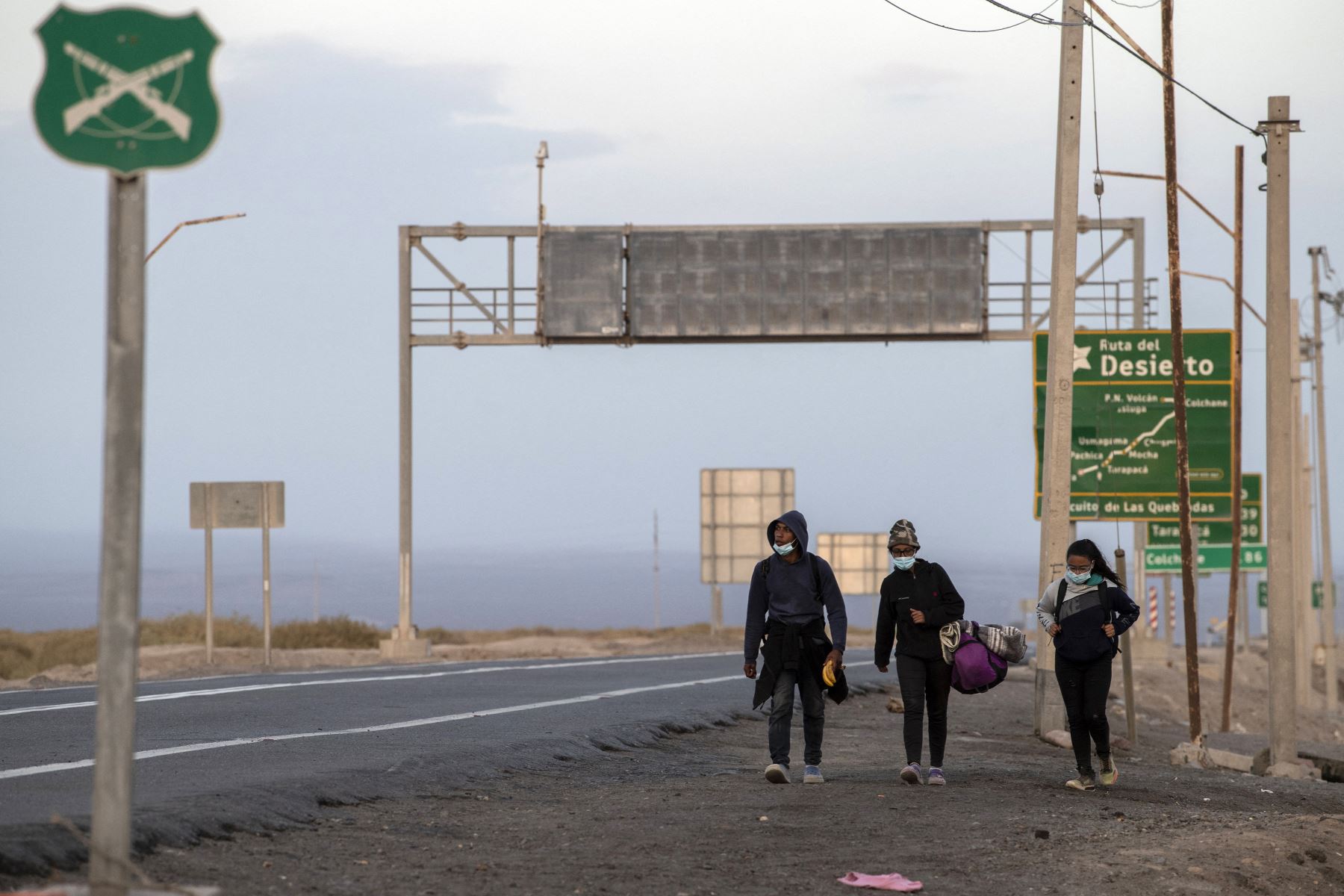 Los migrantes venezolanos Reinaldo, 26, Anyier, 40, y su hija Danyierly, 14, caminan por la carretera camino a Iquique, luego de cruzar desde Bolivia. Foto: AFP