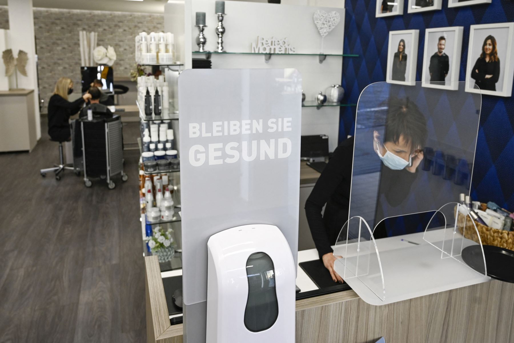 La peluquera Ramona Lesny usa una mascarilla mientras hace una llamada telefónica. En su local se observa un dispensador de desinfectante para sus clientes, en Ludwigsburg, en el sur de Alemania. Foto: AFP