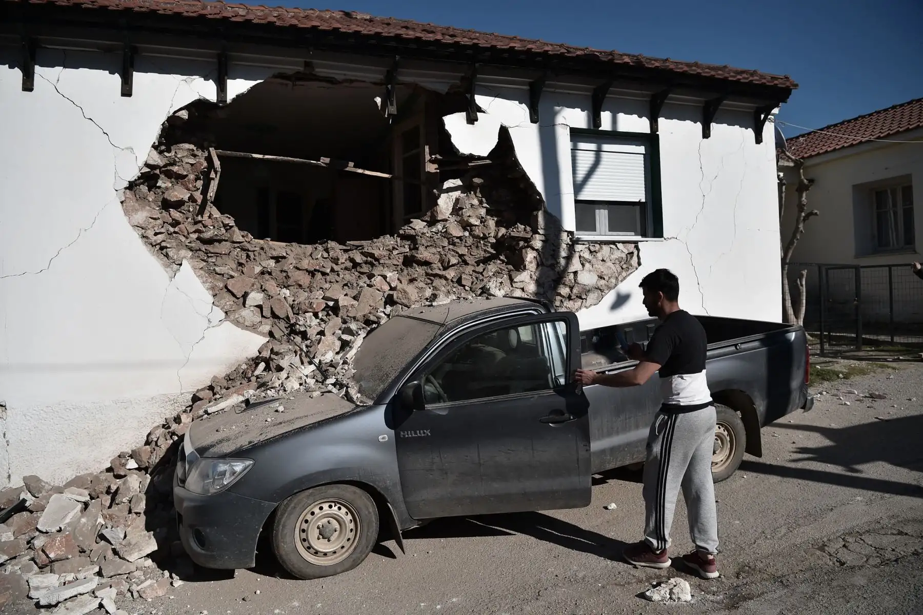 Un hombre observa su automóvil después que un edificio se derrumbara parcialmente en el pueblo de Damasi debido al fuerte sismo de magnitud 6,3 en la región central griega de Tesalia. Foto: AFP