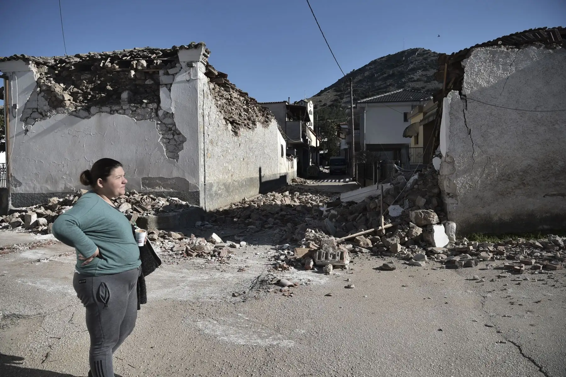 Una mujer se encuentra junto a los viejos edificios dañados en la aldea de Damasi después de que un fuerte sismo de magnitud 6,3 azotara la región central griega de Tesalia. Foto: AFP