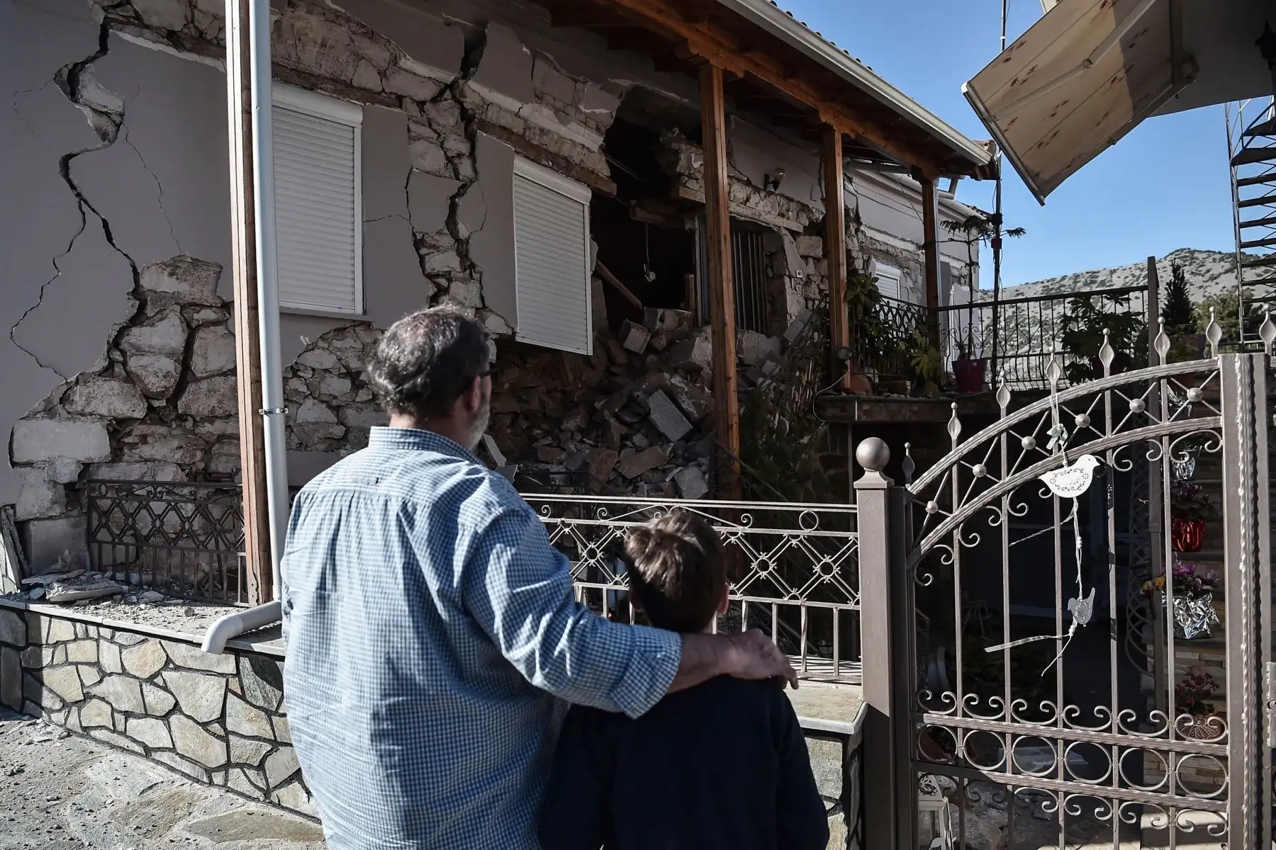 Un padre y un hijo observan una casa dañada en el pueblo de Damas después que un fuerte sismo de magnitud 6,3 azotara la región central griega de Tesalia. Foto: AFP