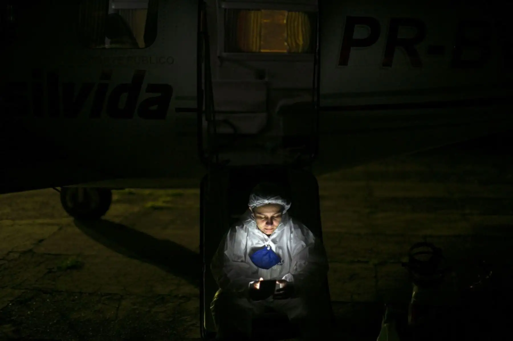 La enfermera Isabela revisa su teléfono móvil al pie de una ambulancia aérea de emergencia mientras espera que llegue un paciente con covid-19 de la Unidad de Atención de Emergencia en Santarem, estado de Pará, Brasil. Foto: AFP