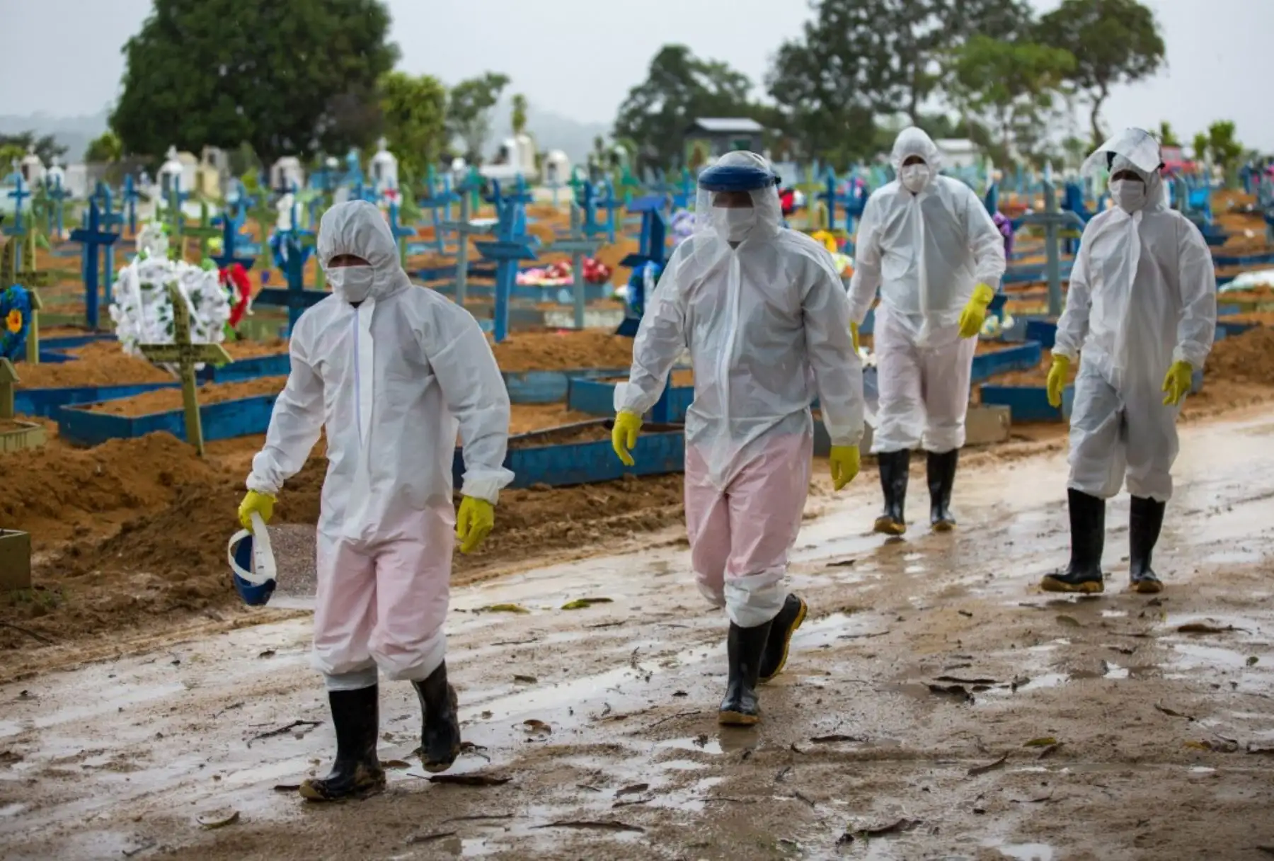 Trabajadores vestidos con trajes protectores caminan frente a las tumbas de las víctimas del covid-19 en el cementerio Nossa Senhora Aparecida, en Manaus, Brasil. Foto: AFP