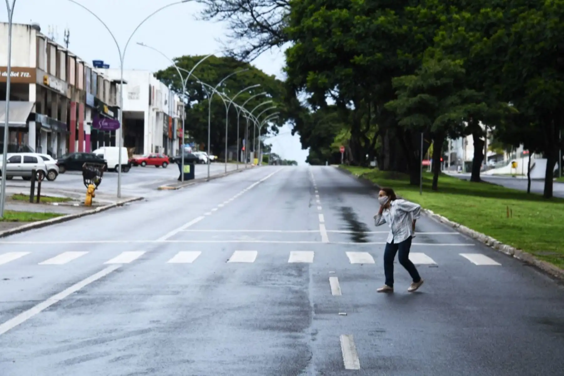 Una mujer cruza una calle en una zona comercial de Brasilia, en el primer día de encierro en la capital brasileña decretado por el gobernador Ibanes Rocha para combatir un aumento de casos del nuevo coronavirus, covid-19. Foto: AFP