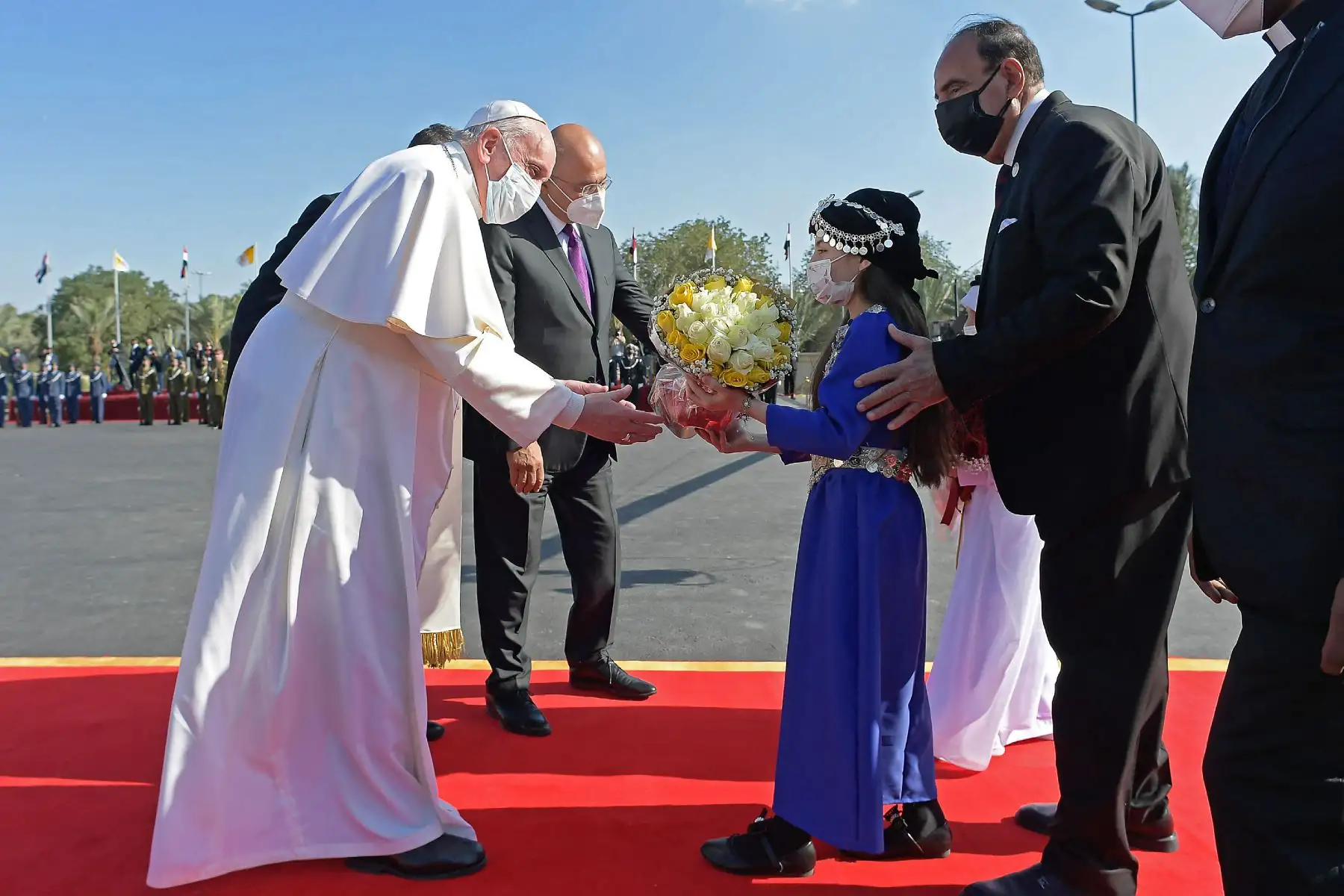 Una niña iraquí con un traje tradicional ofrece al Papa Francisco un ramo de flores en el aeropuerto de Bagdad a su llegada el 5 de marzo de 2021 en la primera visita papal. Foto: AFP