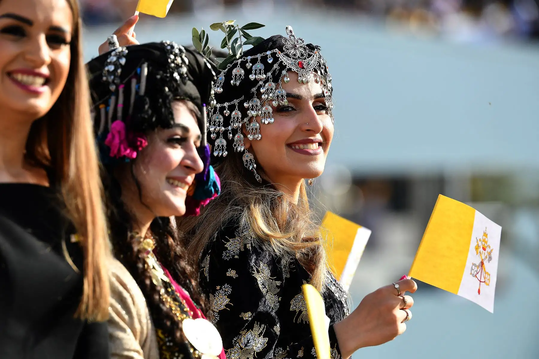 Mujeres jóvenes vestidas con ropa tradicional kurda ondean banderas de la Santa Sede mientras esperan la llegada del Papa Francisco al Estadio Franso Hariri en Arbil, en la capital de la región autónoma kurda del norte de Irak. 
Foto: AFP