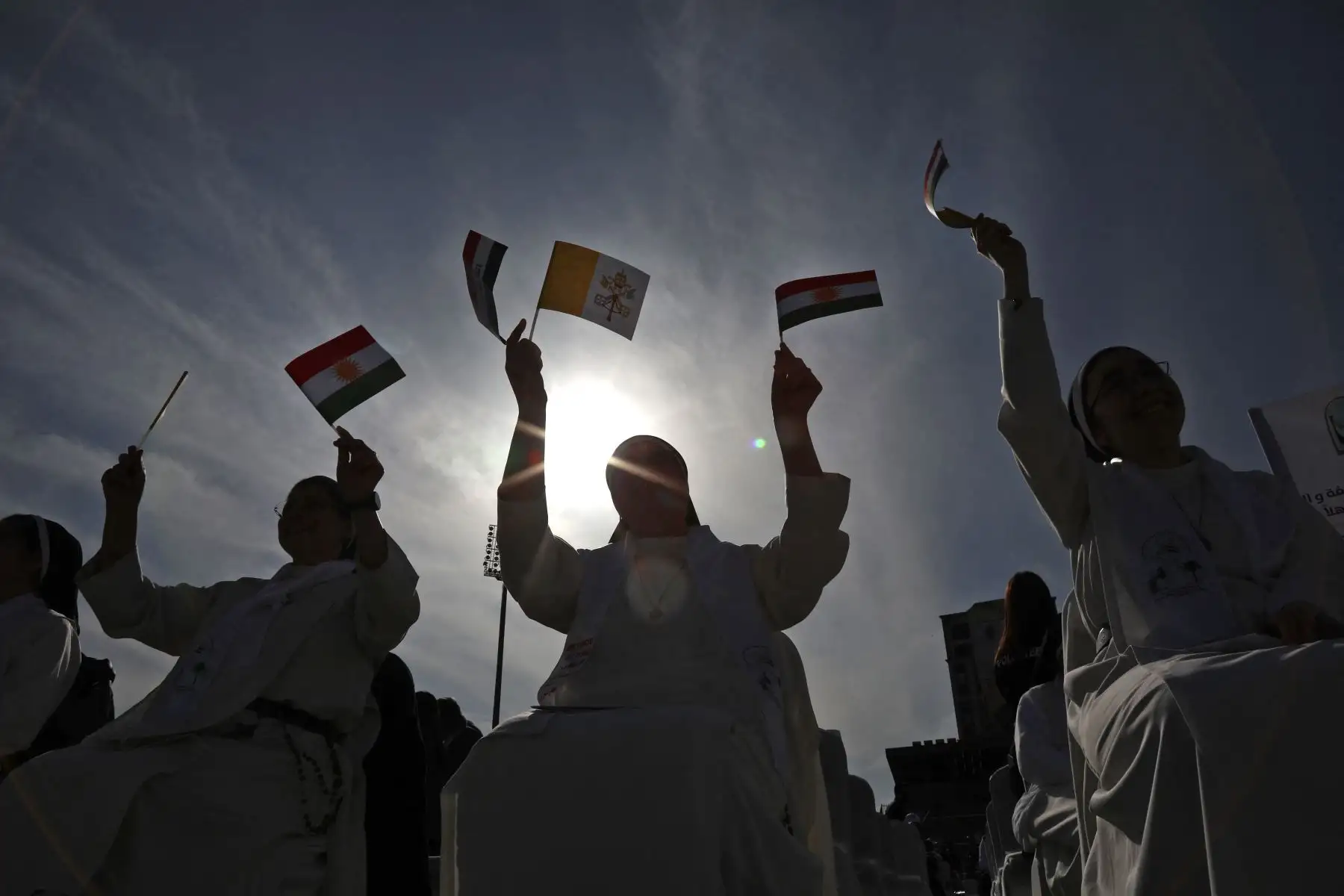 Una monja ondea banderas de Irak, Kurdistán y la Santa Sede mientras espera la llegada del Papa Francisco al Estadio Franso Hariri en Arbil, en la capital de la región autónoma kurda del norte de Irak. 
Foto: AFP
