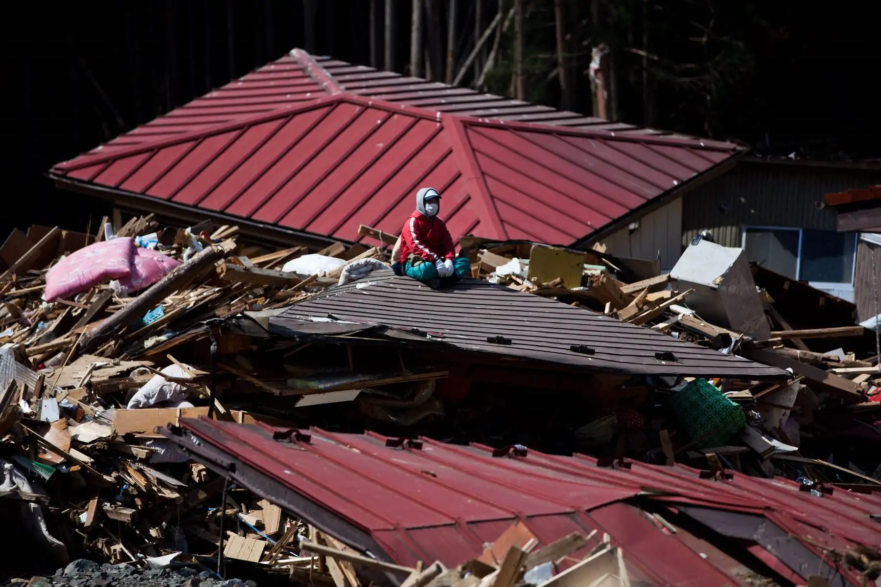El pescador Yutaka Watanabe se sienta en el techo de una casa destruida mientras busca a familiares desaparecidos en Minamisanriku, prefectura de Miyagi Foto: AFP