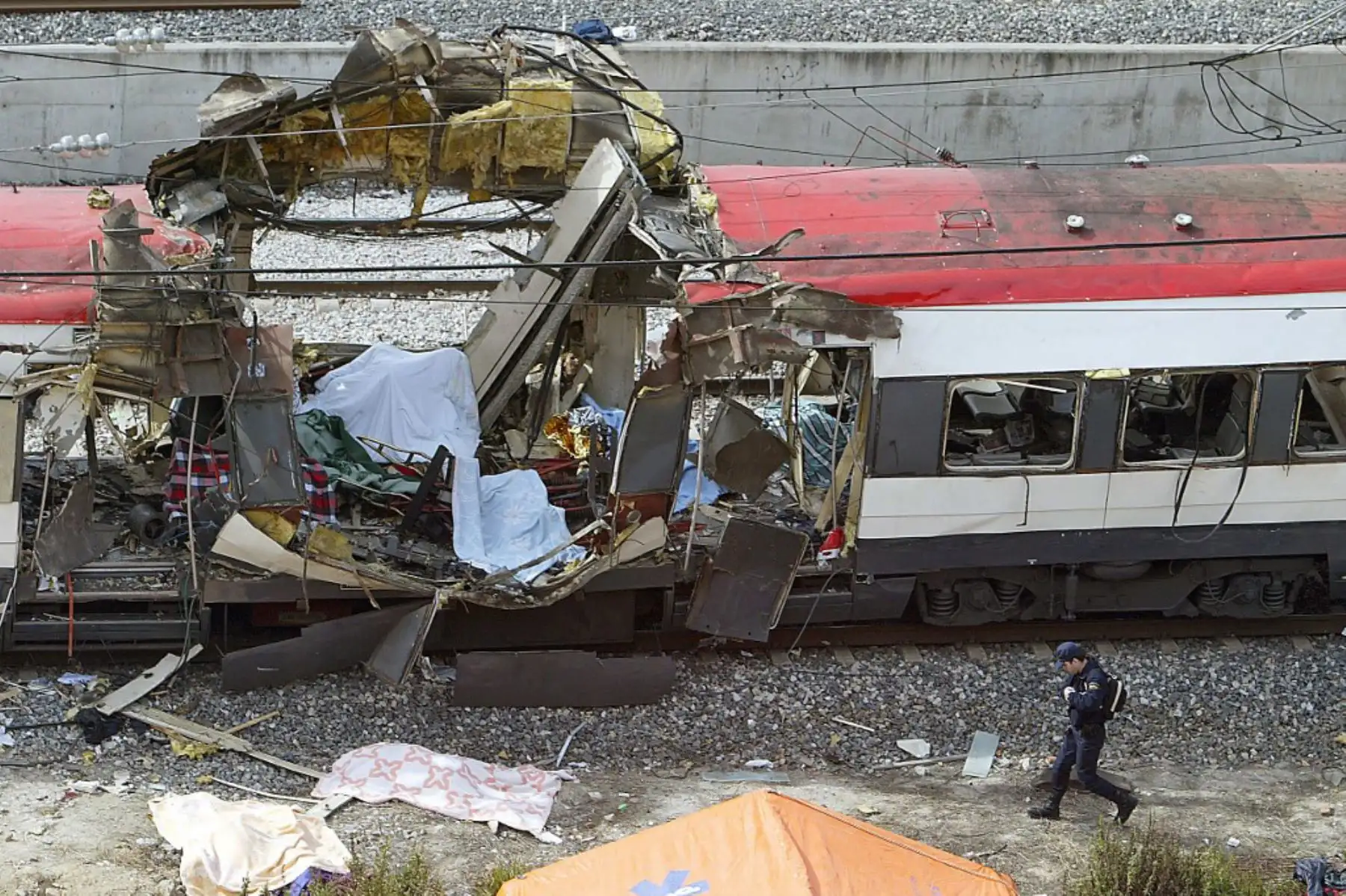 Un policía camina junto al tren que resultó dañado por la explosión de una bomba en la estación de tren de Atocha en Madrid el 11 de marzo de 2004. Cuatro trenes de cercanías en Madrid y sus alrededores fueron alcanzados por explosiones que mataron a 191 personas e hirieron alrededor de 2000 durante la mañana hora punta en un ataque, según las autoridades, se inspiró en Al-Qaeda. Foto: AFP