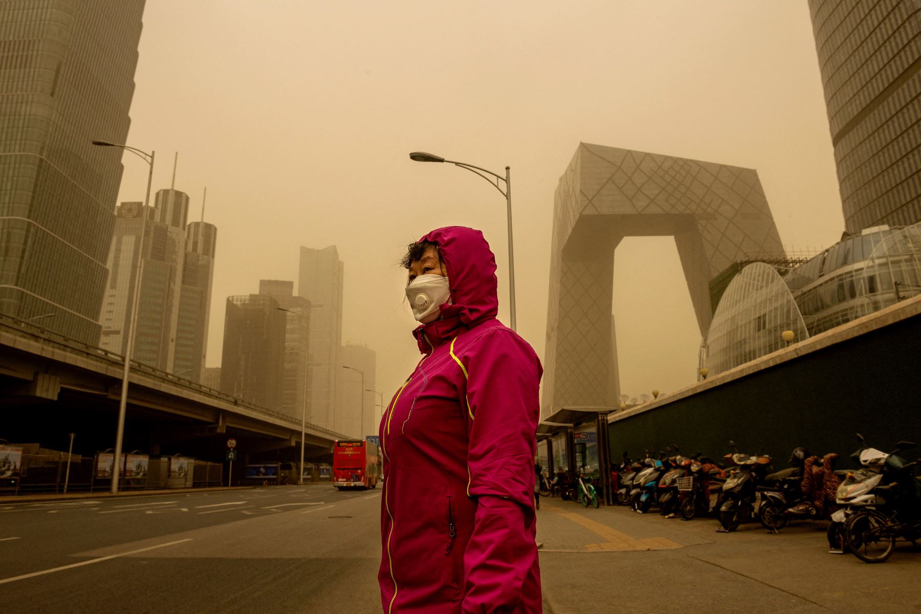Una mujer espera en una parada de autobús durante una tormenta de arena en el distrito financiero de Beijing. Foto: AFP