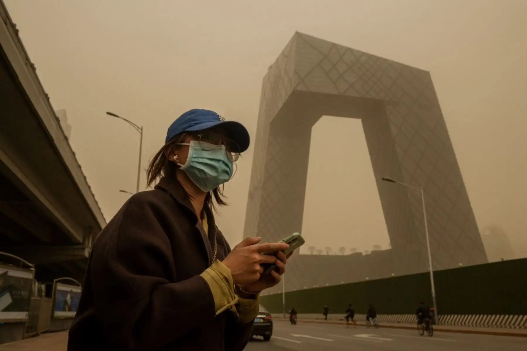 Una mujer cruza una calle durante una tormenta de arena en el distrito financiero de Beijing. Foto: AFP