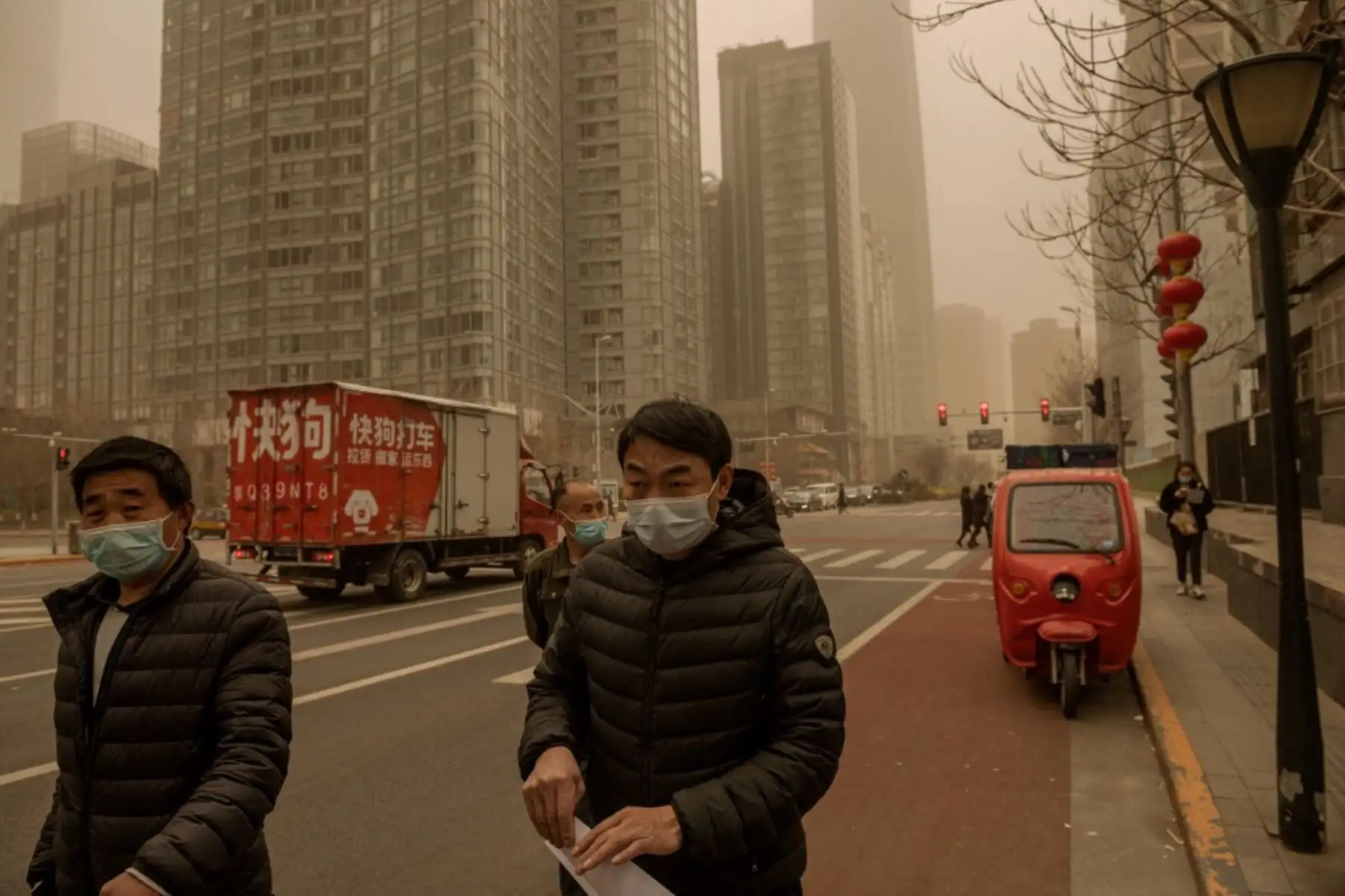 La gente camina por una calle durante una tormenta de arena en el distrito financiero de Beijing. Foto. AFP