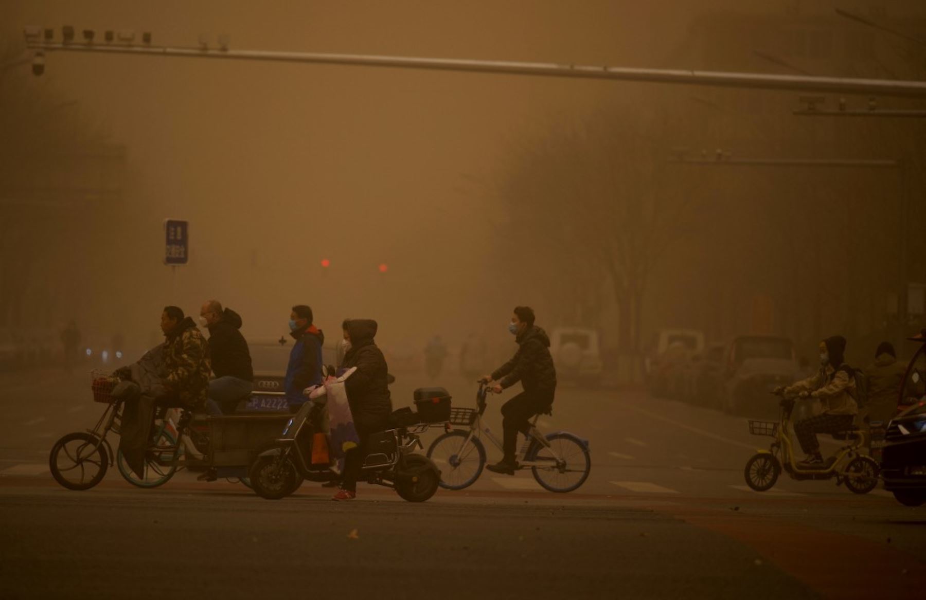 La gente cruza una calle durante una tormenta de arena en Beijing.Foto: AFP