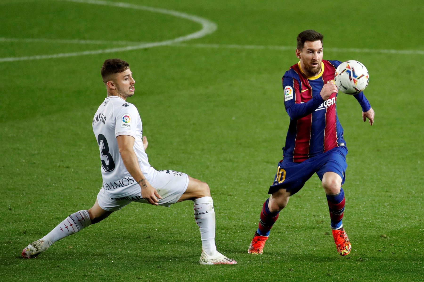 El delantero argentino del FC Barcelona, ​​Leo Messi, se lleva el balón ante el defensa griego del Huesca, Pablo Maffeo, durante el encuentro que se disputa en el Camp Nou. Foto. AFP