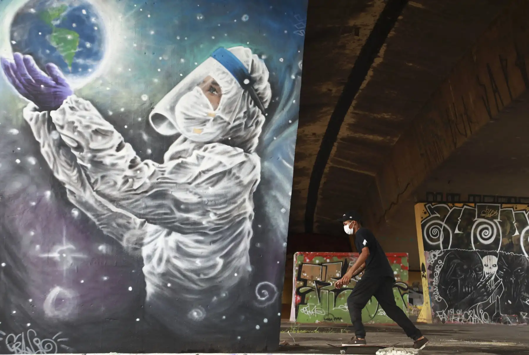 Un hombre patina junto a un grafiti relacionado con el COVID-19 del artista Luciano Cranio, en un parque de patinaje en Sapucaia do Sul, estado de Rio Grande do Sul, Brasil. Foto: AFP