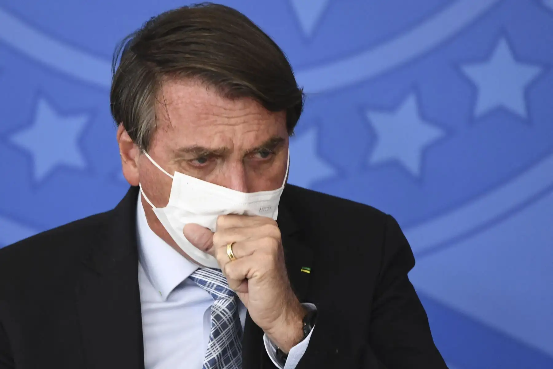 El presidente brasileño, Jair Bolsonaro, tose durante la sanción de la ley que autoriza a los estados, municipios y al sector privado a comprar vacunas contra el COVID-19, en el Palacio Planalto de Brasilia, Brasil. Foto: AFP