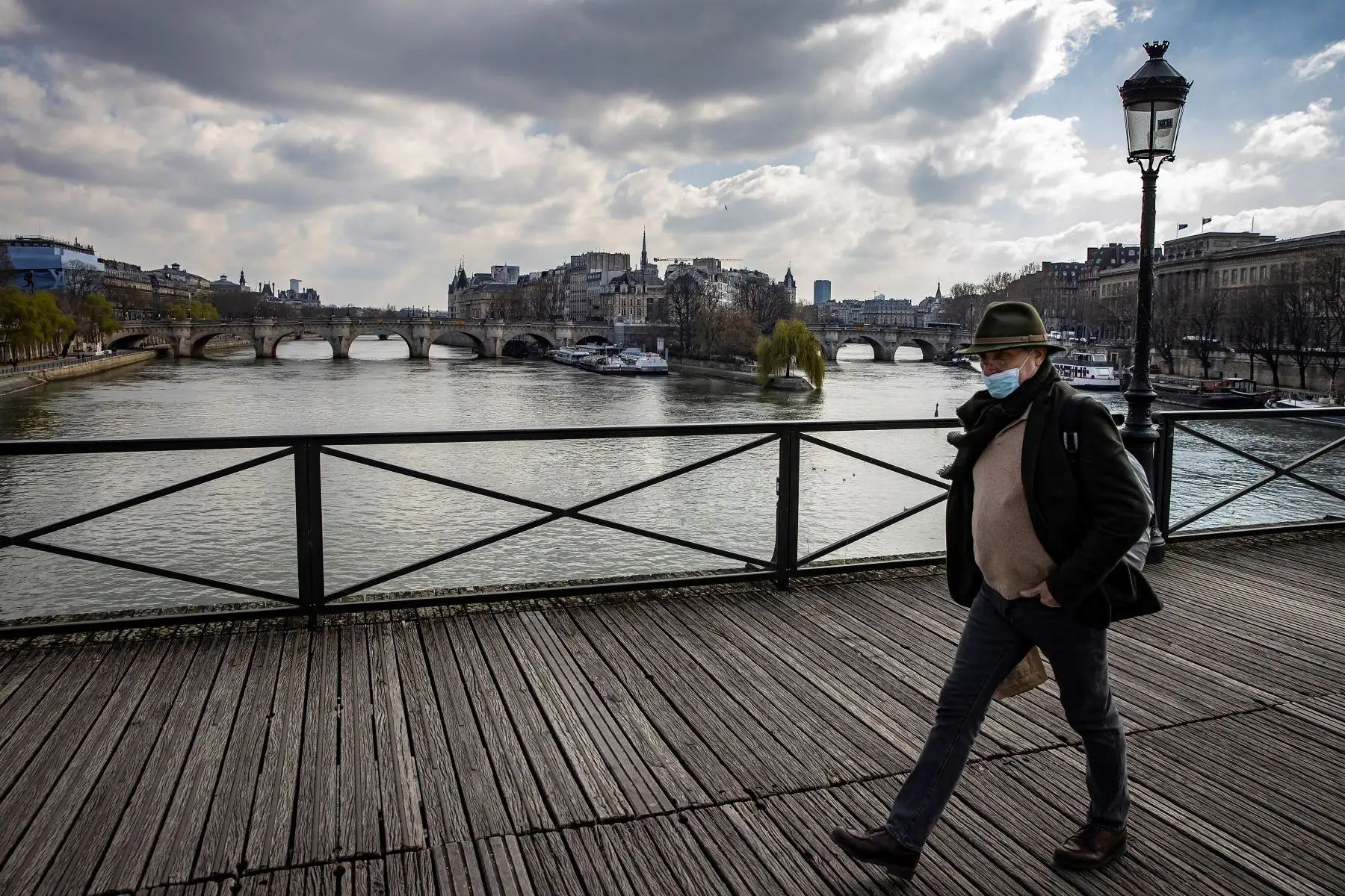 Un peatón con máscara protectora camina a lo largo del río Sena en París, Francia. Foto: EFE