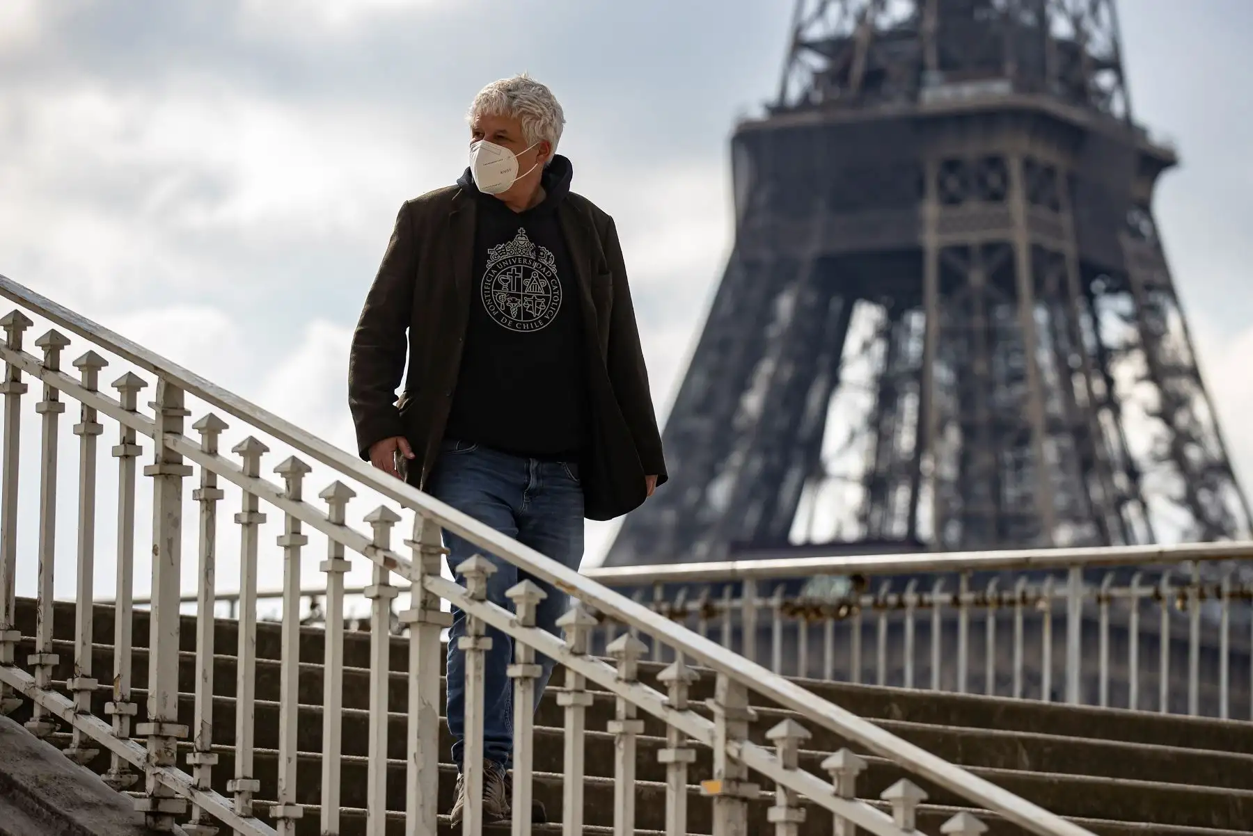 Un peatón con una máscara protectora cruza un puente peatonal cerca de la Torre Eiffel en París, Francia, el 19 de marzo de 2021. Foto: EFE