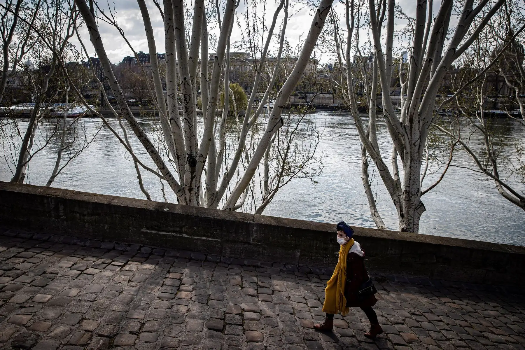 Un peatón con máscara protectora camina a lo largo del río Sena en París, Francia, 19 de marzo de 2021. Foto. Foto: EFE