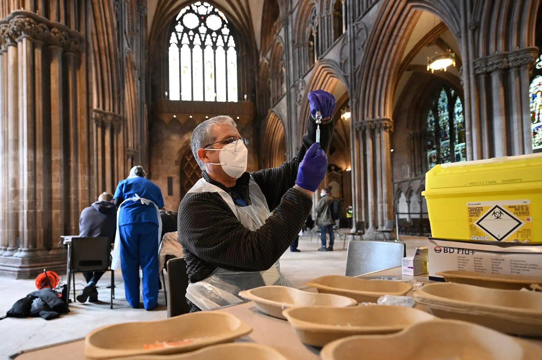 El Dr. Andy Wakeman prepara una dosis de la vacuna Oxford AstraZeneca Covid-19 mientras los pacientes esperan recibir su dosis en la catedral de Lichfield, que se ha convertido en un centro de vacunación temporal, en Lichfield, Inglaterra. Foto: AFP
