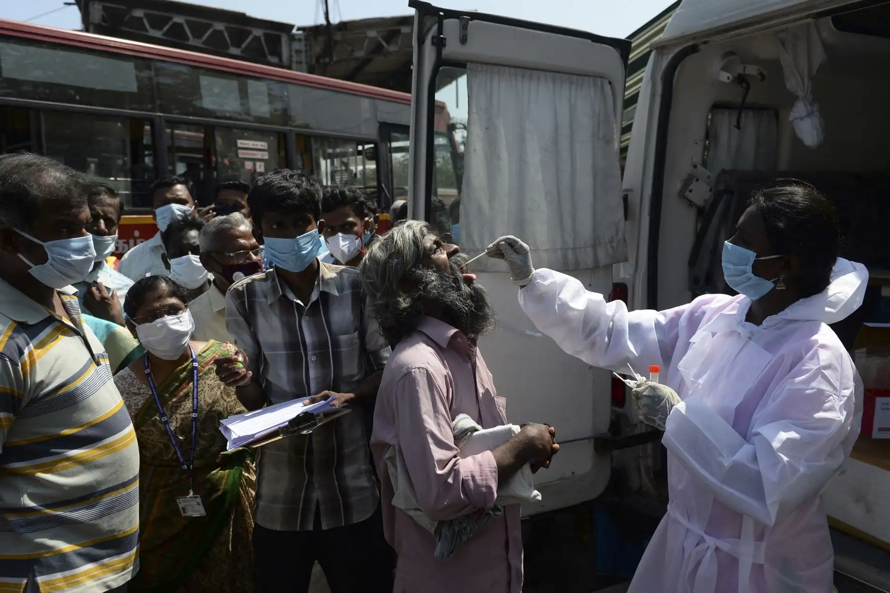 Un trabajador de la salud toma una muestra de un hisopo de un hombre para una prueba de coronavirus RT-PCR Covid-19 en una terminal de autobuses en Chennai, India. Foto: AFP