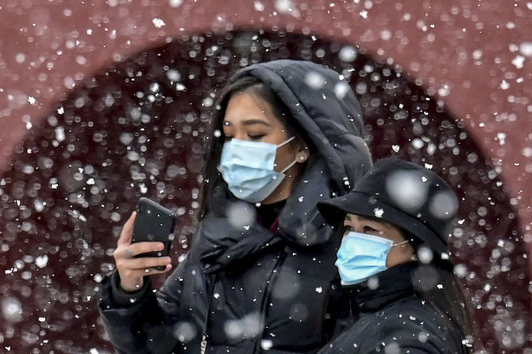 Dos mujeres con máscaras faciales como protección contra la enfermedad del coronavirus se toman una selfie durante la nevada en el centro de Moscú el 8 de marzo de 2021. Foto: AFP