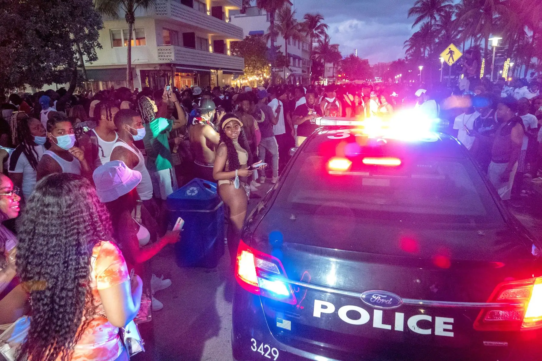 Turistas observan un auto de agentes del Departamento de Policía de Miami Beach que recorren las playas arrestando a quienes no cumplen con el toque de queda que comienza desde las 20:00 en South Beach durante las vacaciones de primavera, el 20 de marzo de 2021. Foto: EFE