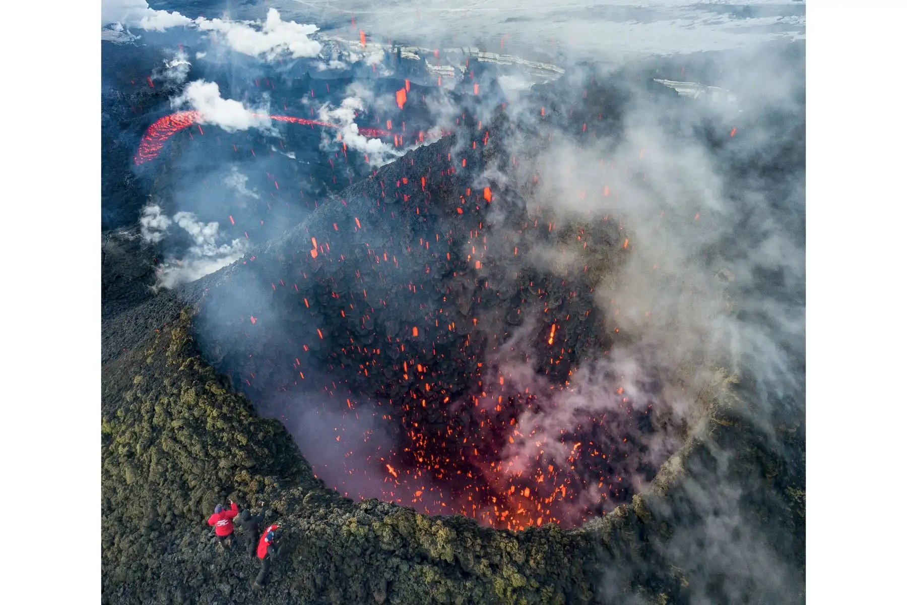 Una foto tomada con un dron, el 16 de marzo de 2021, muestra a miembros de un escuadrón local de búsqueda y rescate tomando fotografías de la erupción del volcán Klyuchevskoy en la península de Kamchatka, en el extremo oriental de Rusia. Foto: AFP