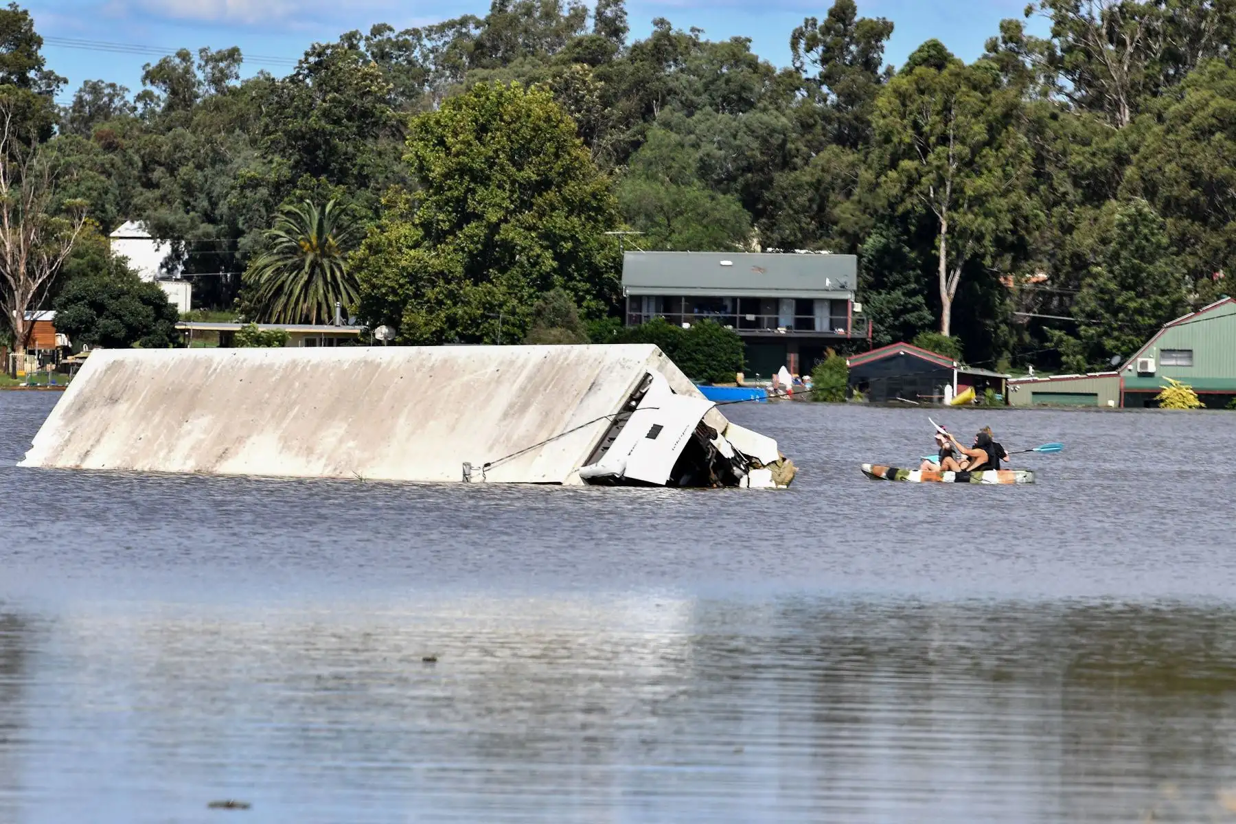La gente rema junto a un contenedor  rodeado por las inundaciones en una zona residencial del suburbio de Windsor en el noroeste de Sydney  después de que lluvias torrenciales azotaran el sureste de Australia durante días.
Foto: AFP