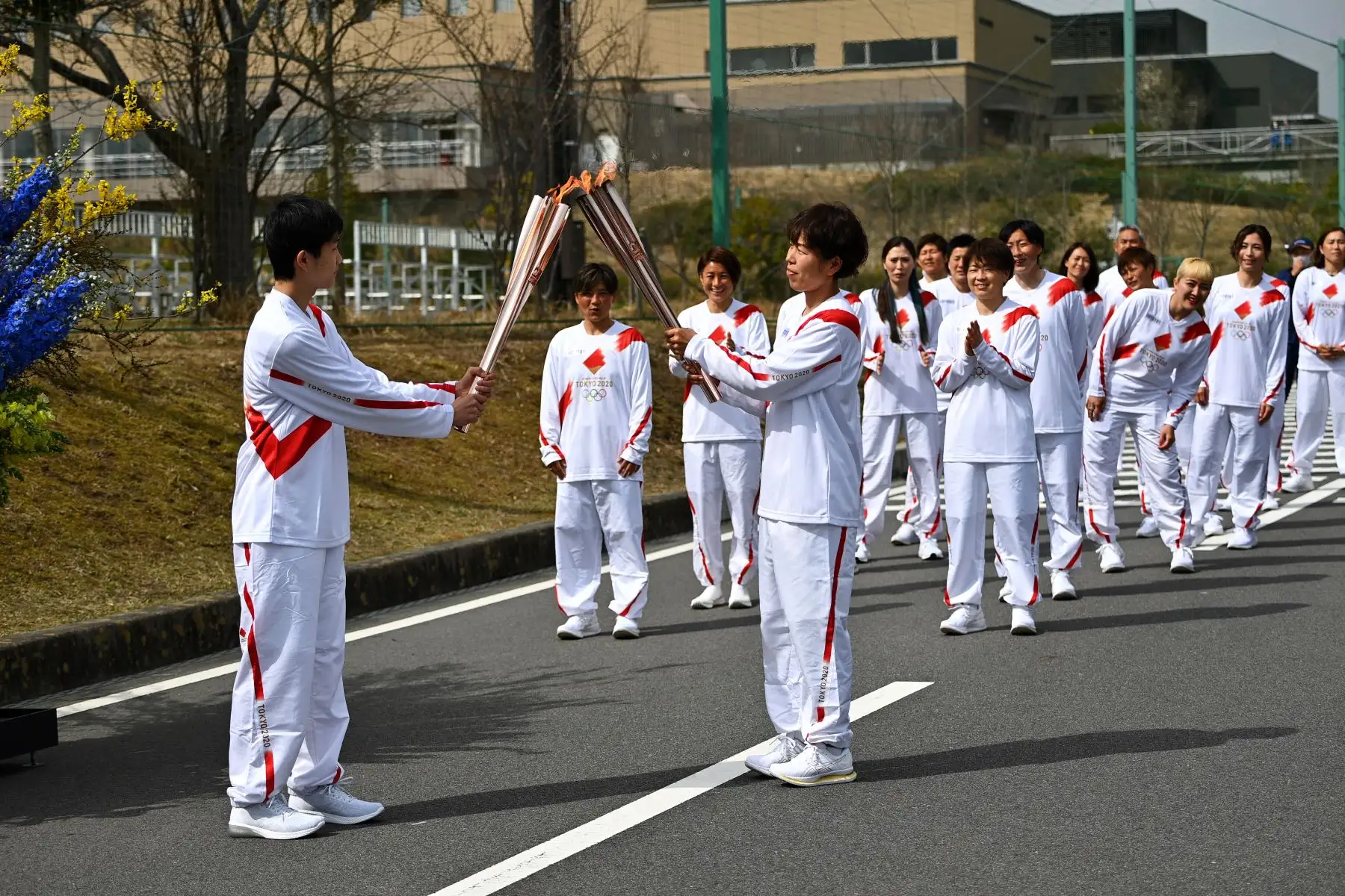 La portadora de la antorcha japonesa Azusa Iwashimizu (C), miembro del equipo nacional de fútbol femenino de Japón, pasa la llama olímpica a una estudiante de secundaria y nativa de Fukushima. Foto: AFP
