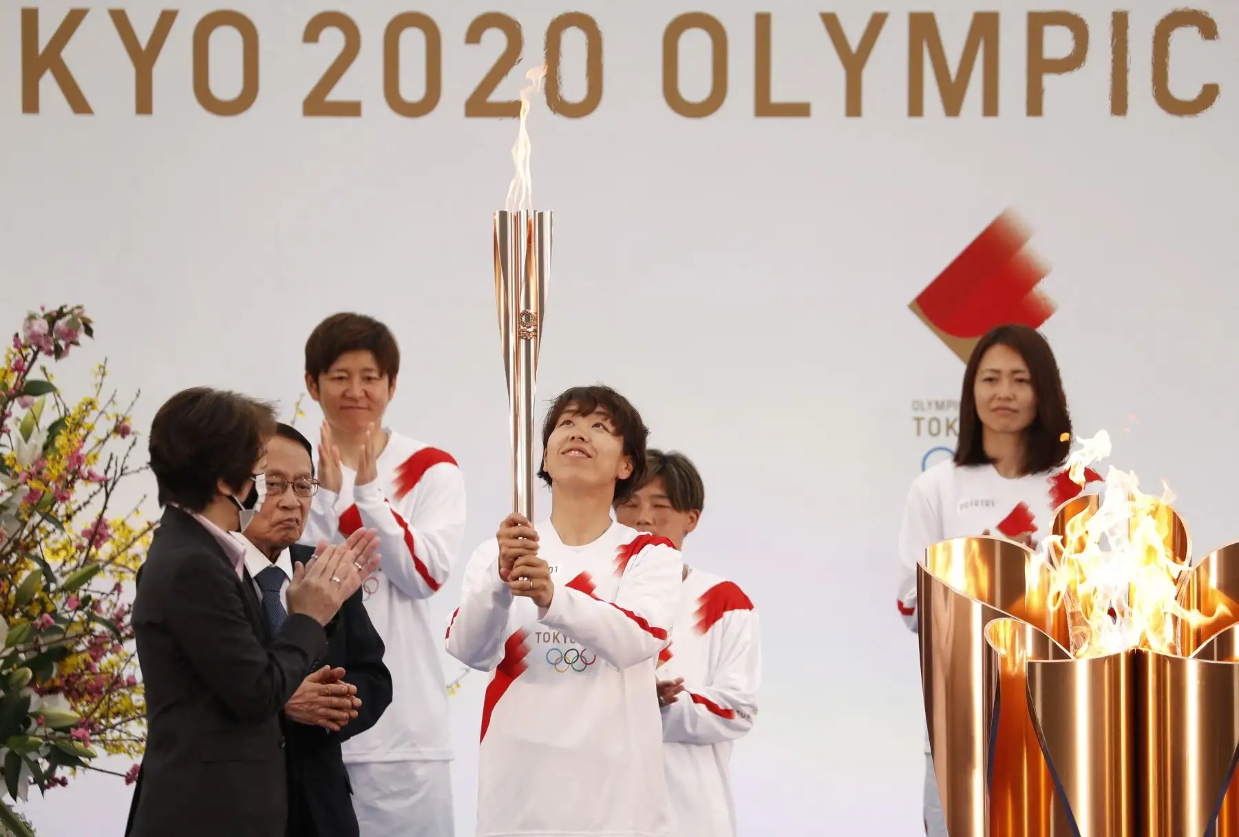 La presidenta de Tokio 2020, Seiko Hashimoto (izq.), Aplaude cuando un miembro del equipo nacional femenino de fútbol de Japón (C) lleva la antorcha en el primer día del relevo de la antorcha en Naraha, prefectura de Fukushima. Foto: AFP