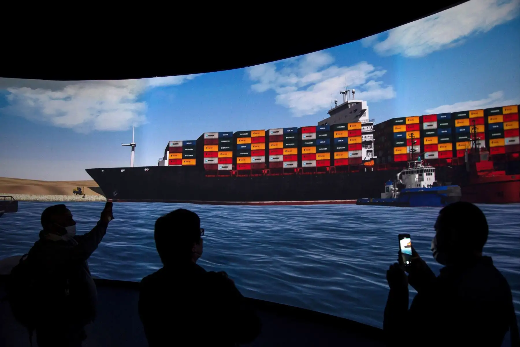 Reporteros se paran frente a una pantalla que muestra una simulación del tirón del buque portacontenedores Ever Given en el Canal de Suez, demostrado durante una rueda de prensa. Foto: EFE