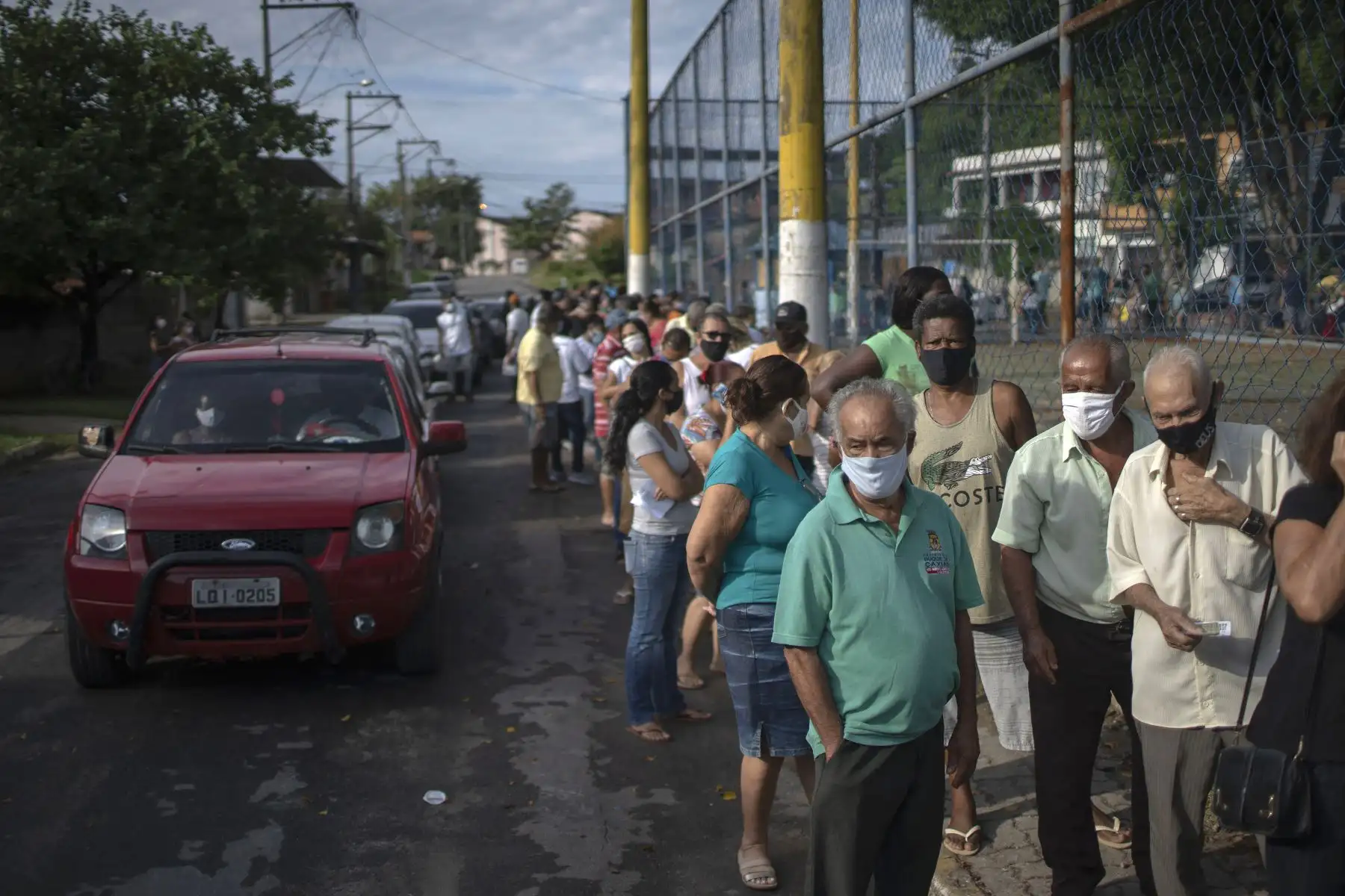 Personas con mascarillas hacen cola para recibir una dosis de la vacuna covid-19 en un centro de vacunación en la plaza Cangulo, en Duque de Caxias, estado de Río de Janeiro, Brasil, el 30 de marzo de 2021. Foto: AFP