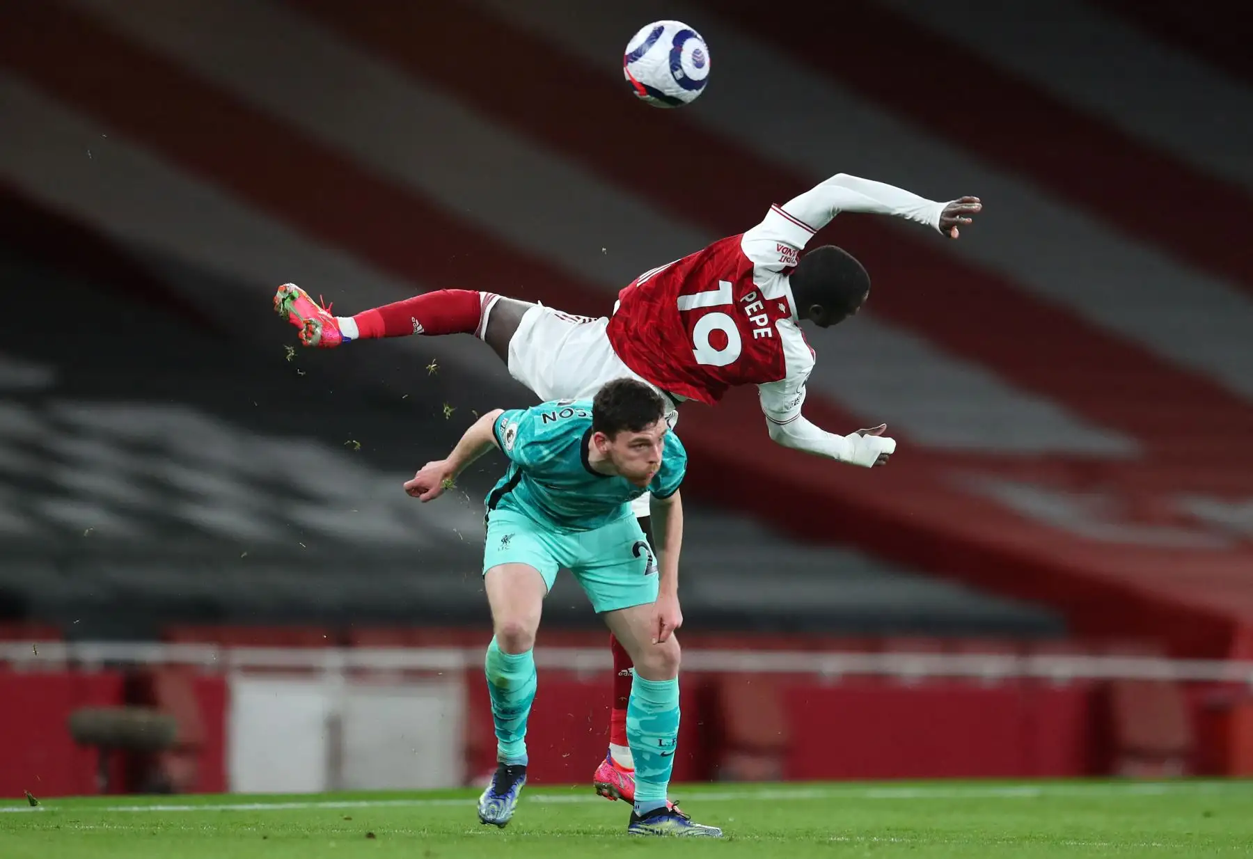 El defensor escocés del Liverpool Andrew Robertson (abajo) compite por el balón contra el mediocampista marfileño nacido en Francia del Arsenal, Nicolas Pepe (arriba) durante el partido de fútbol de la Premier League inglesa entre el Arsenal y el Liverpool en el Emirates Stadium de Londres. Foto: AFP