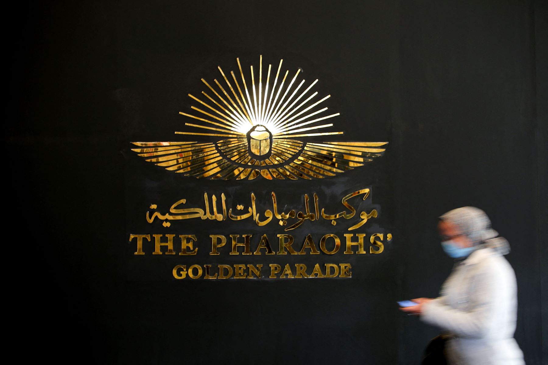 Una mujer con una máscara protectora pasa junto a un logotipo dorado en el Museo de la Civilización Egipcia (NMEC), en el distrito de Fustat del Viejo Cairo, durante su reapertura oficial, después de la ceremonia del Desfile Dorado de los faraones.
Foto: AFP