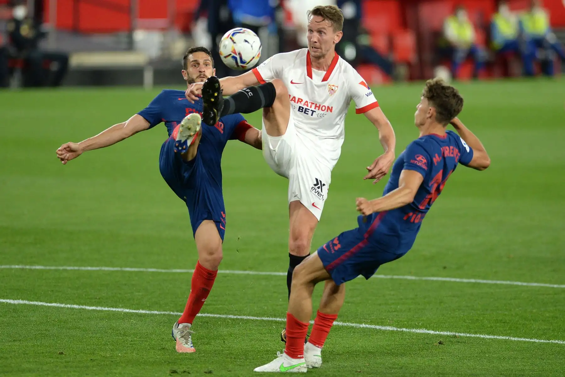 El delantero holandés del Sevilla Luuk De Jong (C) desafía al centrocampista español del Atlético de Madrid Koke (L) y el centrocampista español del Atlético de Madrid Marcos Llorente durante el partido de fútbol de la Liga española entre el Sevilla FC y el Club Atlético de Madrid en el estadio Ramón Sánchez Pizjuan de Sevilla