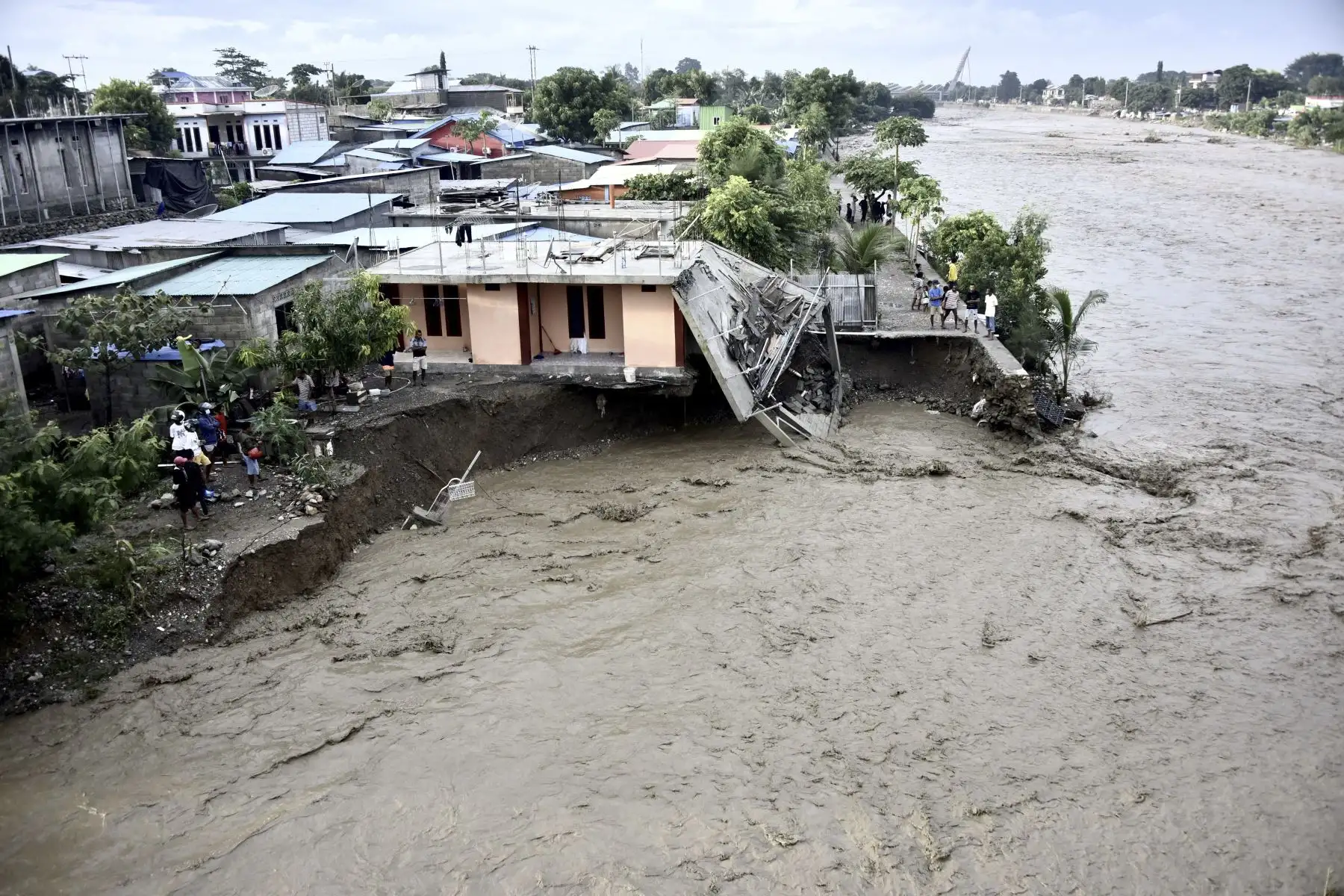 Los residentes se paran a lo largo de la orilla junto a las casas dañadas después  que las fuertes lluvias y vientos azotaron la capital de Dili, en Timor Oriental. Foto: AFP