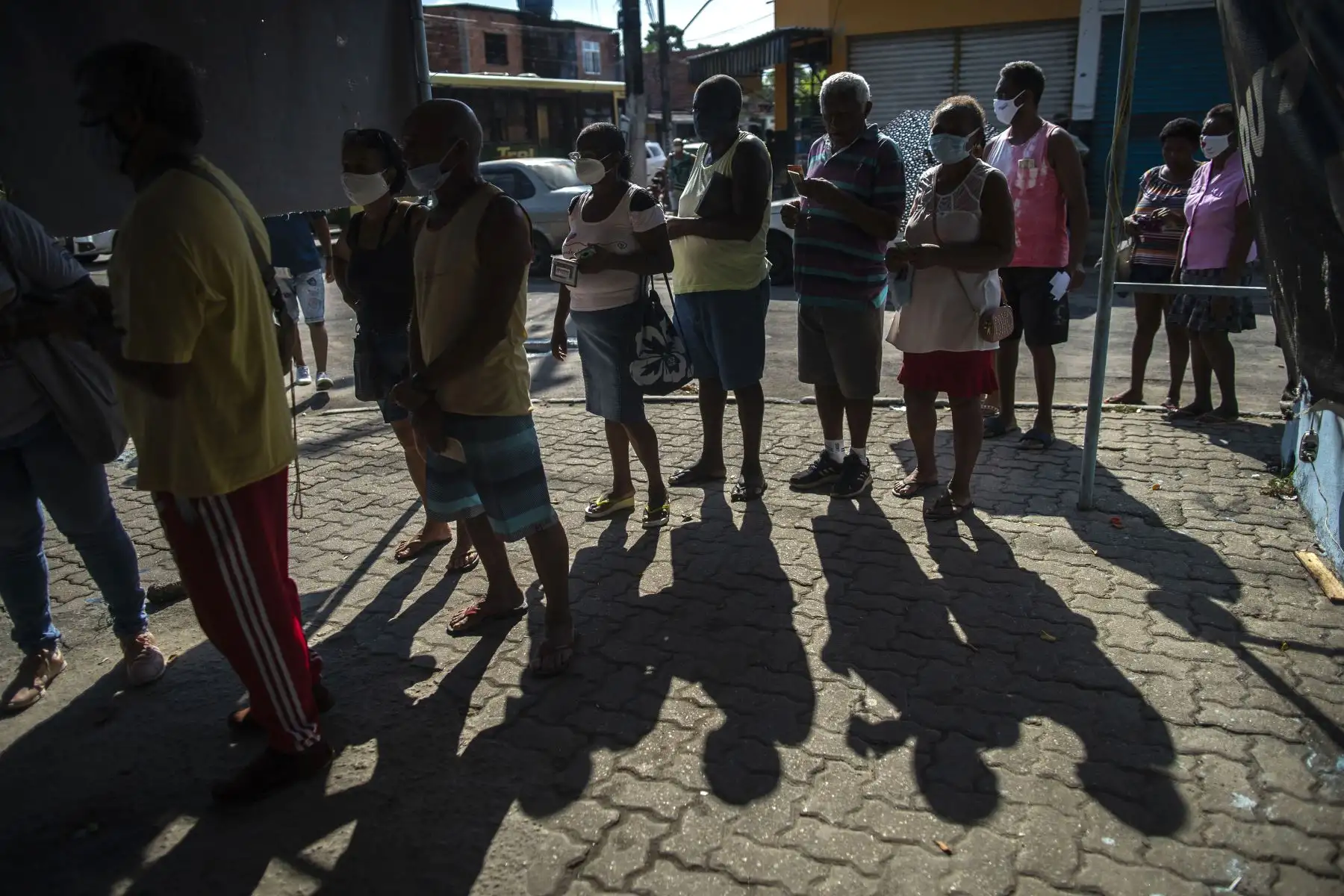 Personas con mascarillas hacen cola para su turno para recibir una dosis de la vacuna COVID-19 en un centro de vacunación en la plaza Cangulo, barrio Saracuruna, en Duque de Caxias, estado de Río de Janeiro, Brasil, el 30 de marzo de 2021. Foto: AFP