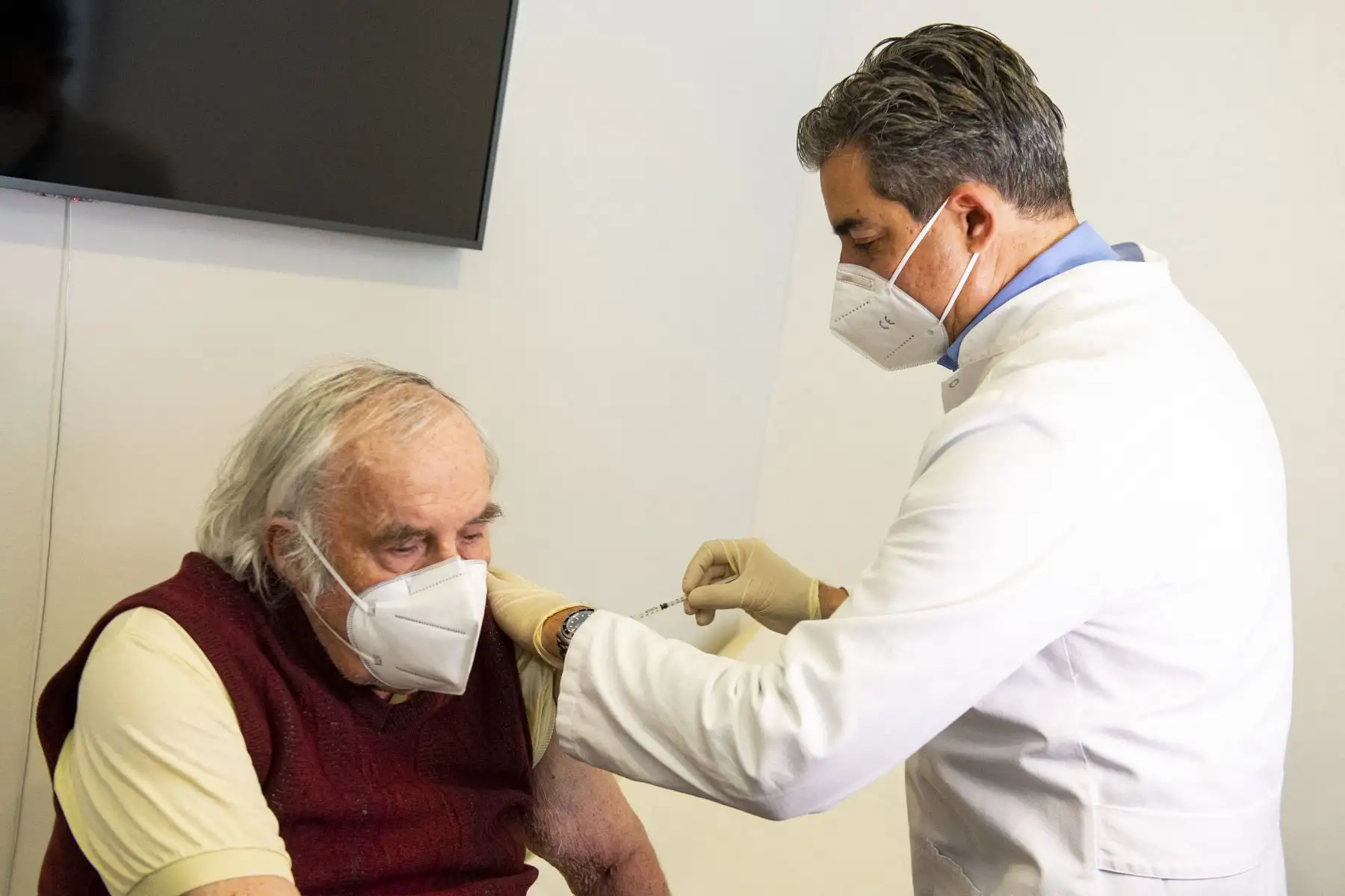 El médico general Oliver Abbushi vacuna al paciente Helmuth Mueller con la vacuna de AstraZeneca contra el coronavirus en Deisenhofen, sur de Alemania, el 31 de marzo de 2021. Foto: AFP