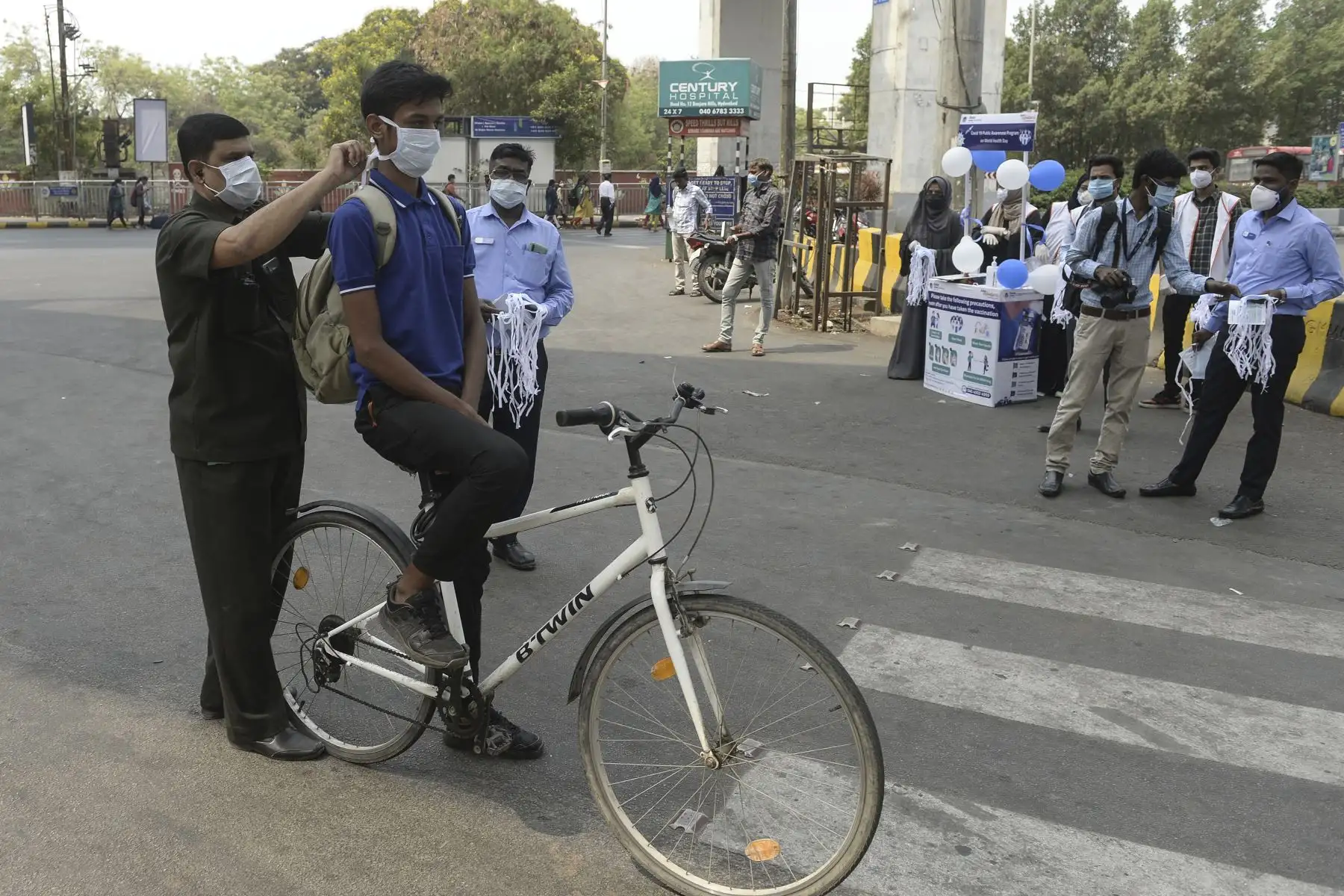 Un trabajador de la salud ayuda a un ciclista a ponerse una mascarilla durante una campaña de concientización contra la propagación del coronavirus Covid-19, en Hyderabad, India. Foto: AFP