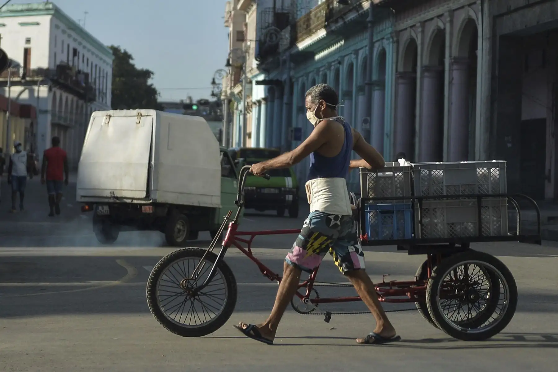 Un hombre con mascarilla transporta alimentos en su bicicleta por una calle de La Habana, el 6 de abril de 2021: Foto. AFP