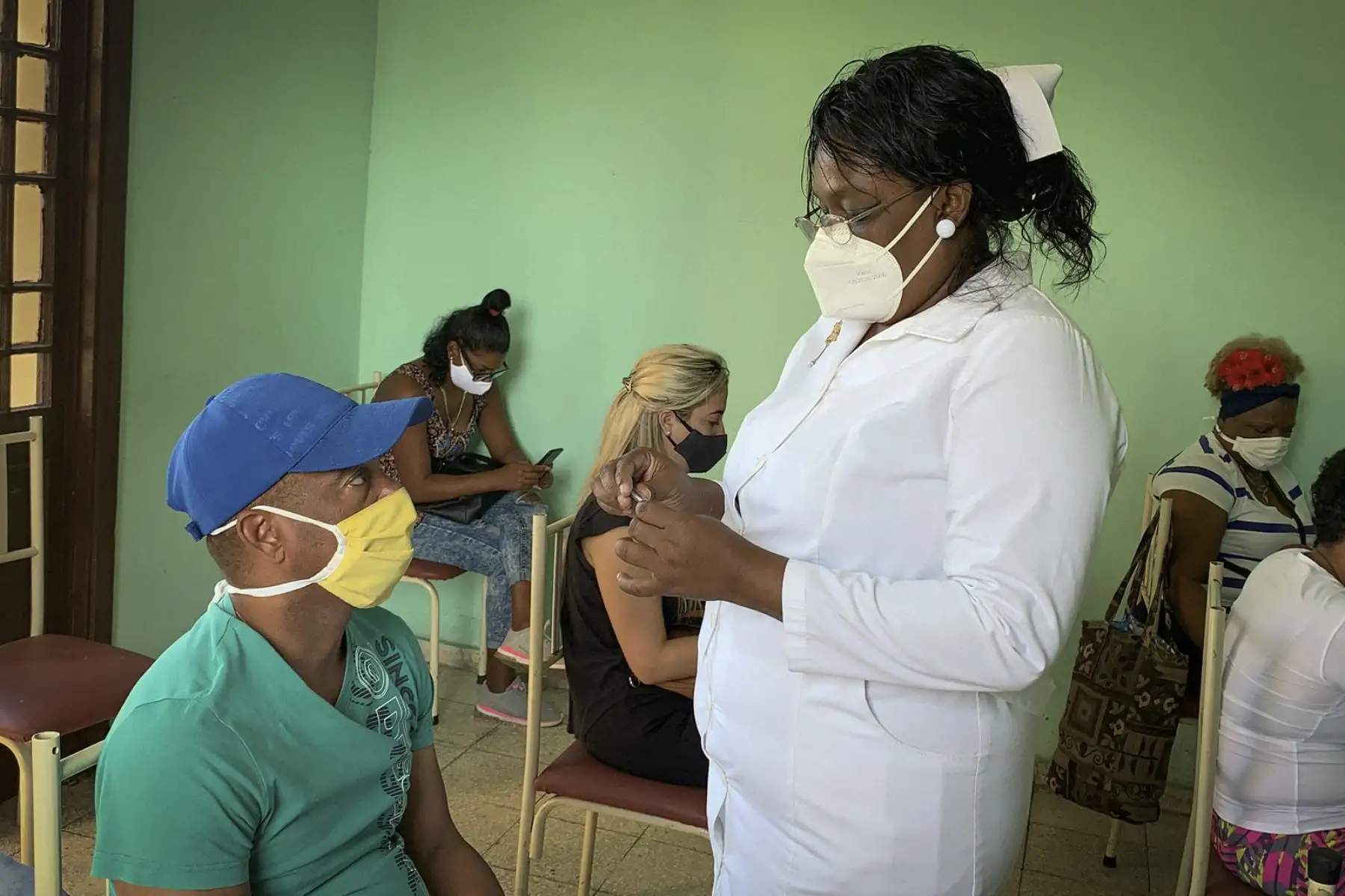Una enfermera controla la temperatura de los cubanos pertenecientes al sistema de salud quienes esperan ser inoculados con la vacuna cubana Soberana 2, el 24 de marzo de 2021, en la Havana. Foto: AFP