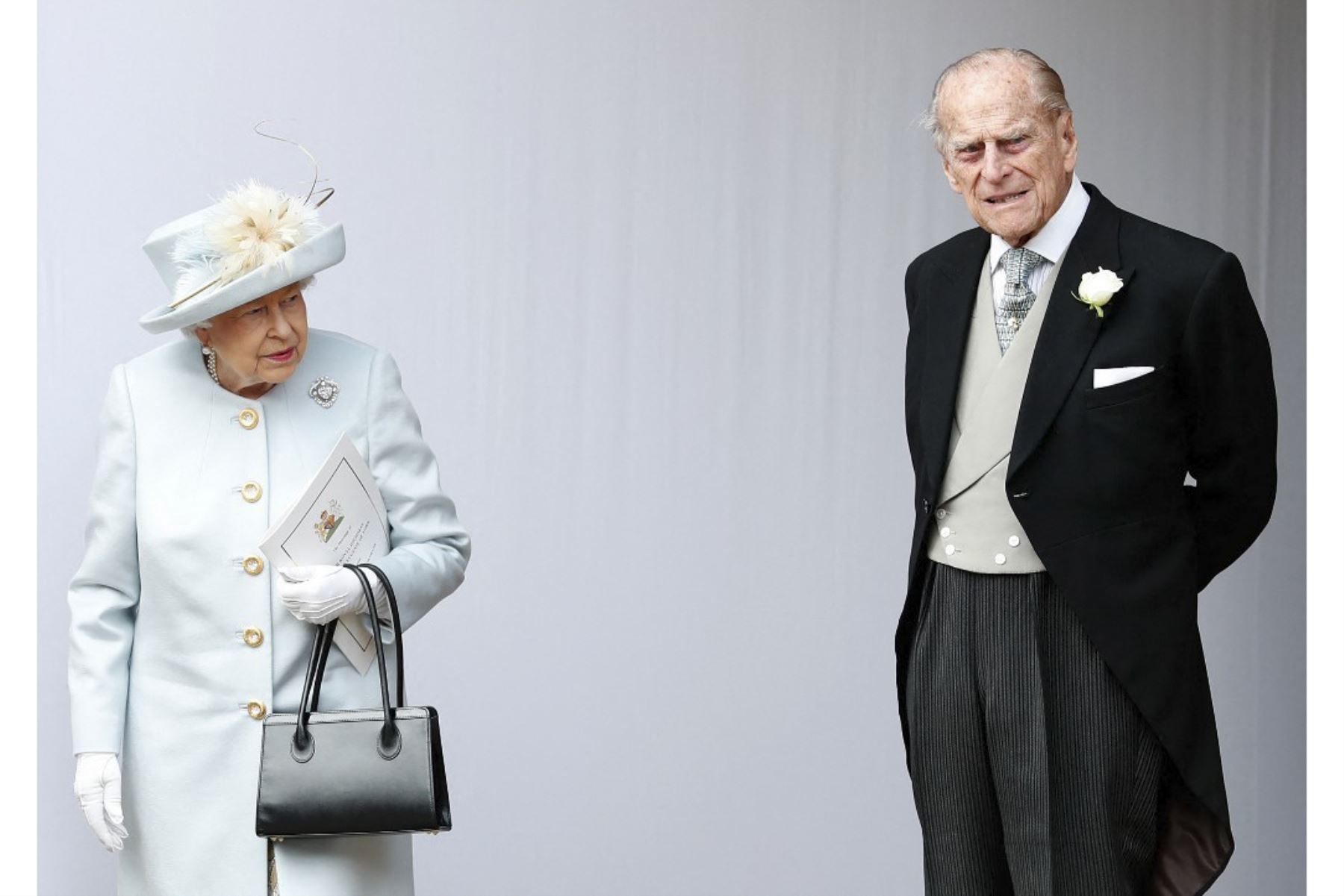 La Reina Isabel II de Gran Bretaña y el Príncipe Felipe de Gran Bretaña, Duque de Edimburgo esperan a que pase el carruaje con la Princesa Eugenia de York y su esposo Jack Brooksbank al comienzo de la procesión después de su ceremonia de boda en la Capilla de St George, Windsor Castle, en Windsor, el 12 de octubre de 2018. Foto: AFP