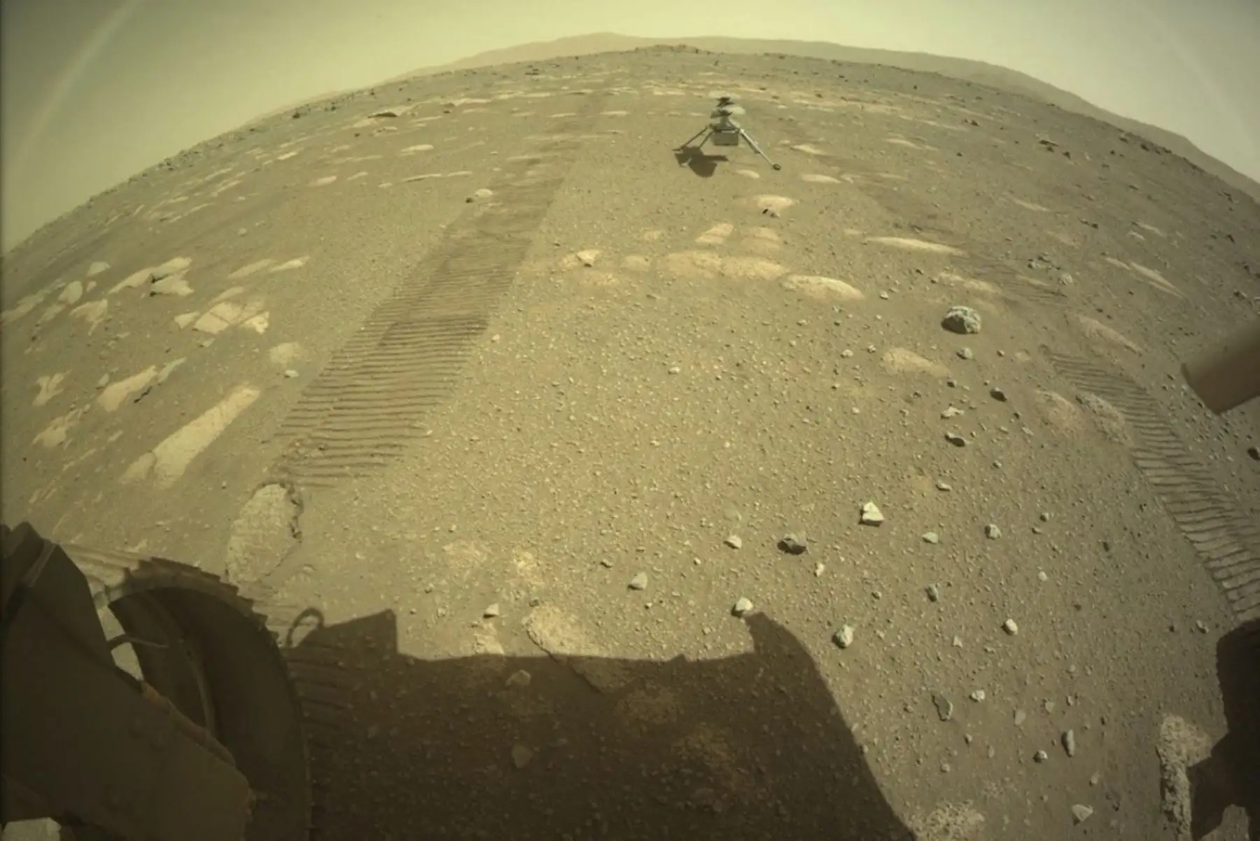 Esta foto de la NASA muestra el helicóptero Ingenuity Mars de la NASA en el suelo detrás del rover Perseverance. Foto: AFP