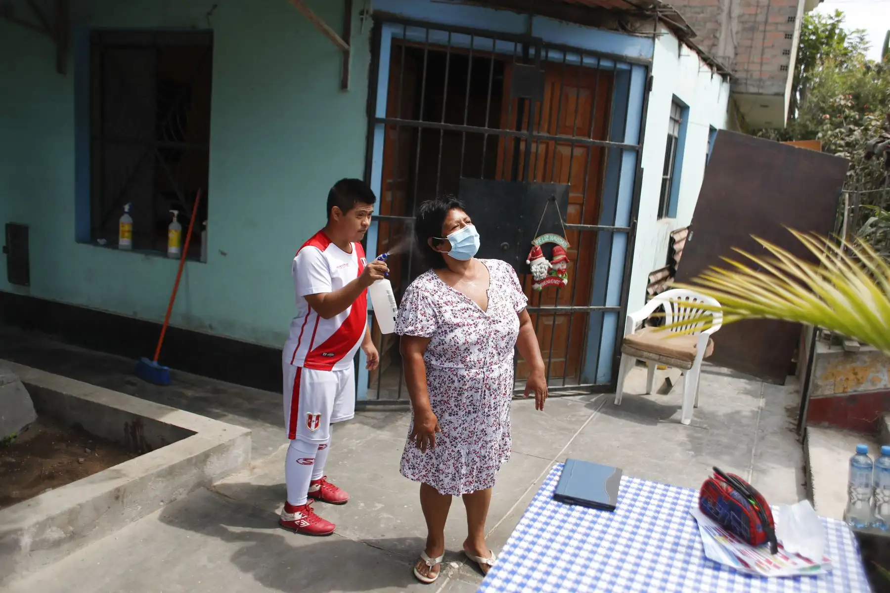 Joseph Flores se encarga de rociar alcohol cada vez que algún familiar regresa a casa. Foto: ANDINA/Renato Pajuelo