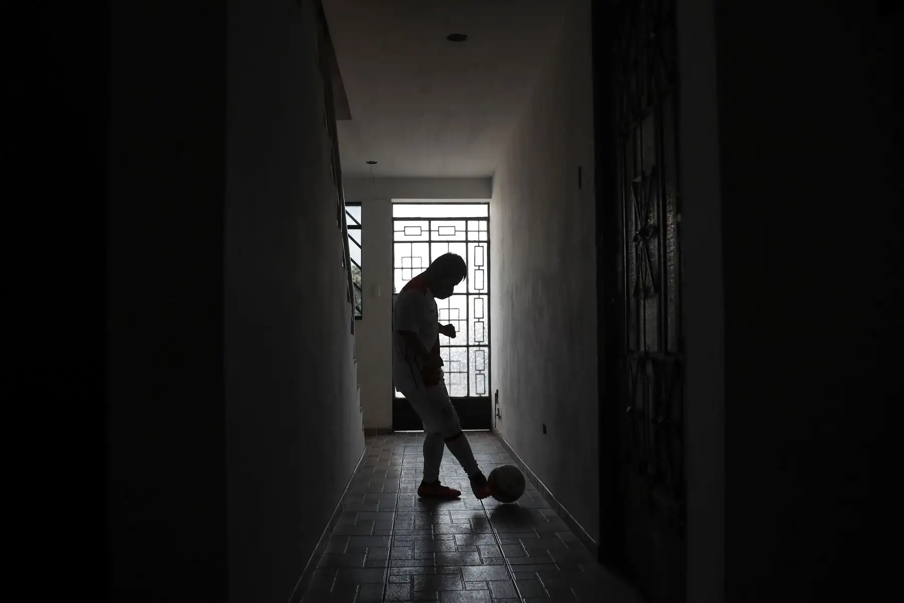 Ronny Flores practica algunas tiros contra la pared en el pasillo de su hogar debido al confinamiento que acata, en Villa El Salvador. Foto: ANDINA/Renato Pajuelo