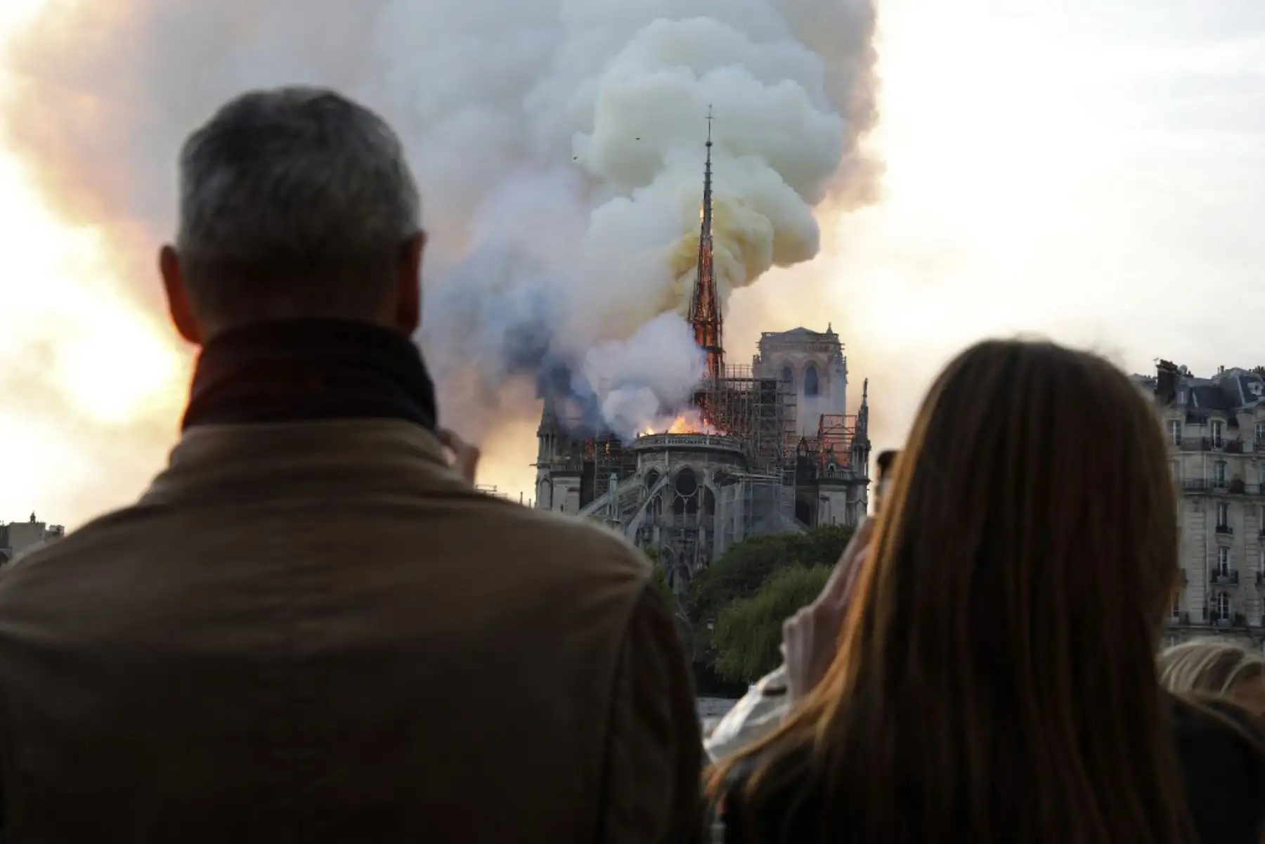 La gente reacciona al ver cómo las llamas envuelven el techo de la catedral de Notre-Dame de París en la capital francesa, París.

Foto: AFP